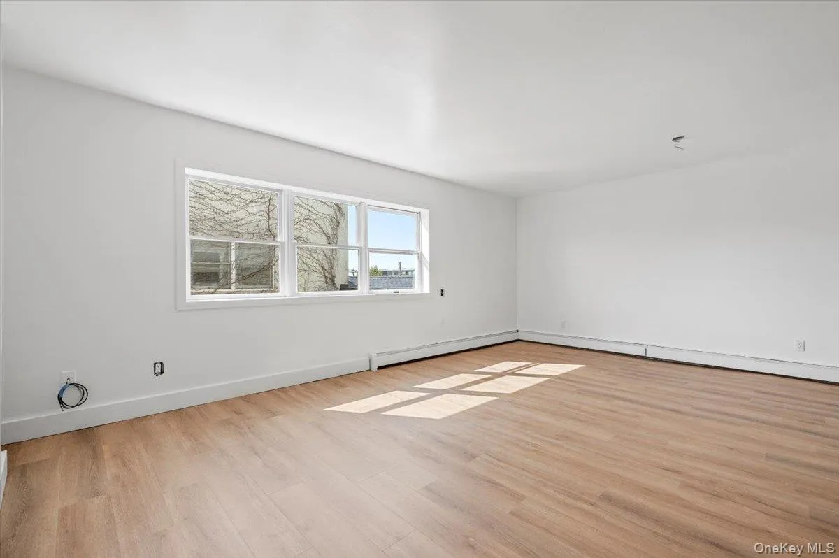 Unfurnished room featuring light wood-type flooring, a baseboard heating unit, and baseboard heating Unfurnished room featuring light wood-type flooring, a baseboard heating unit, and baseboard heating