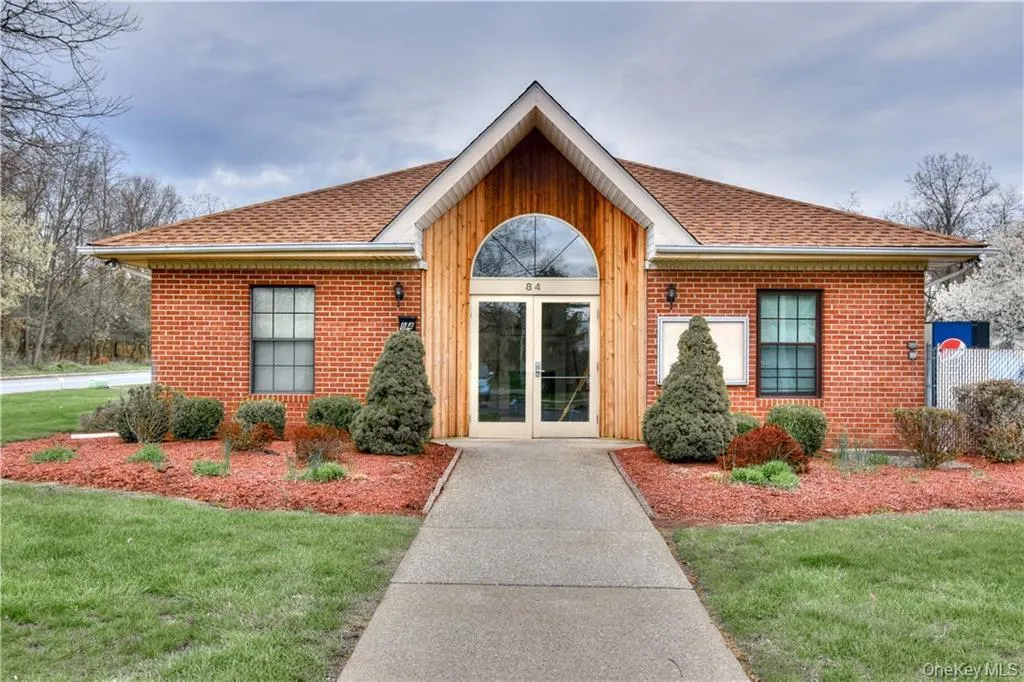 Entrance to property featuring a lawn, roof with shingles, and brick siding Entrance to property featuring a lawn, roof with shingles, and brick siding
