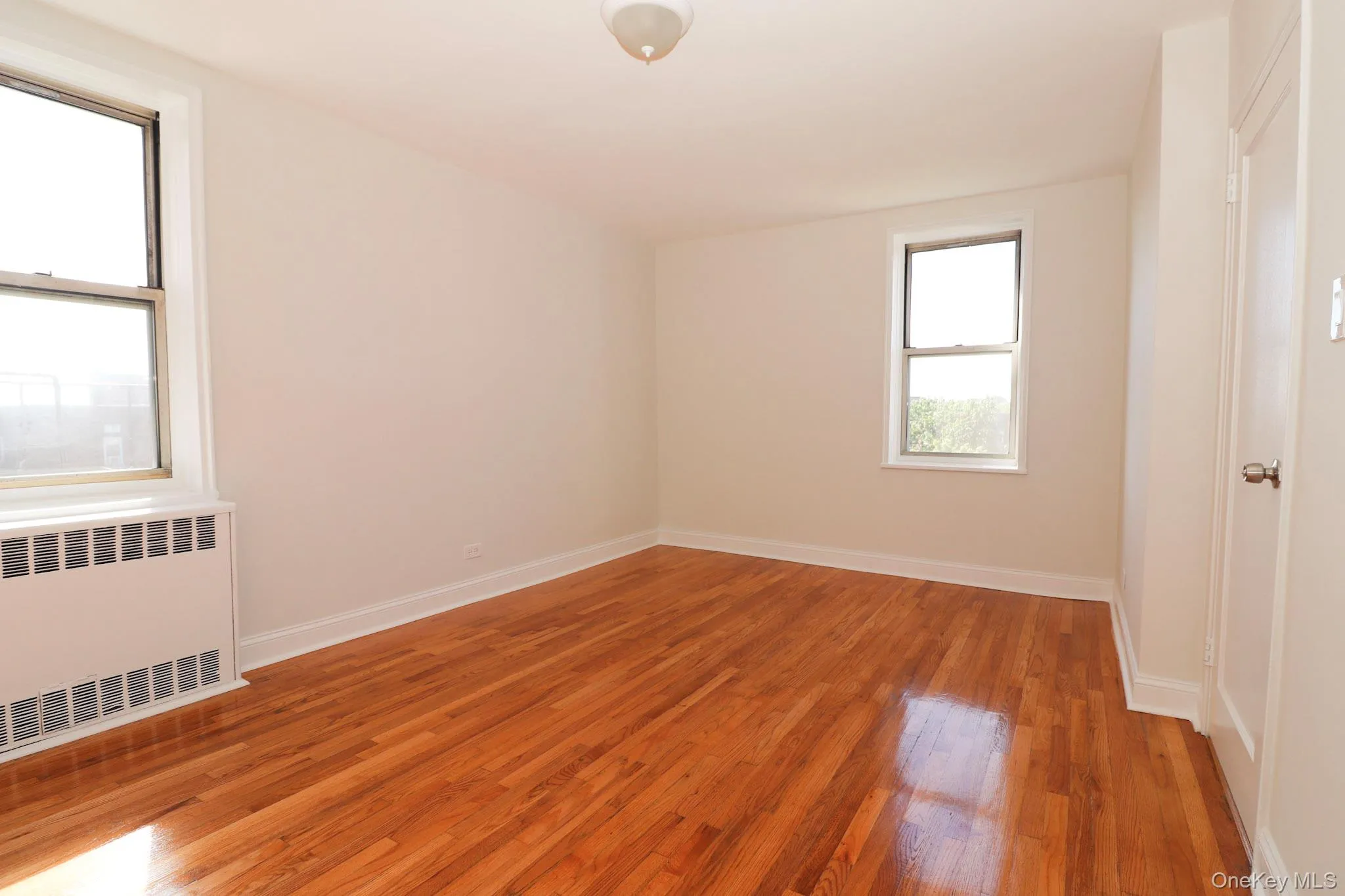 Spare room with radiator and light wood finished floors Spare room with radiator and light wood finished floors
