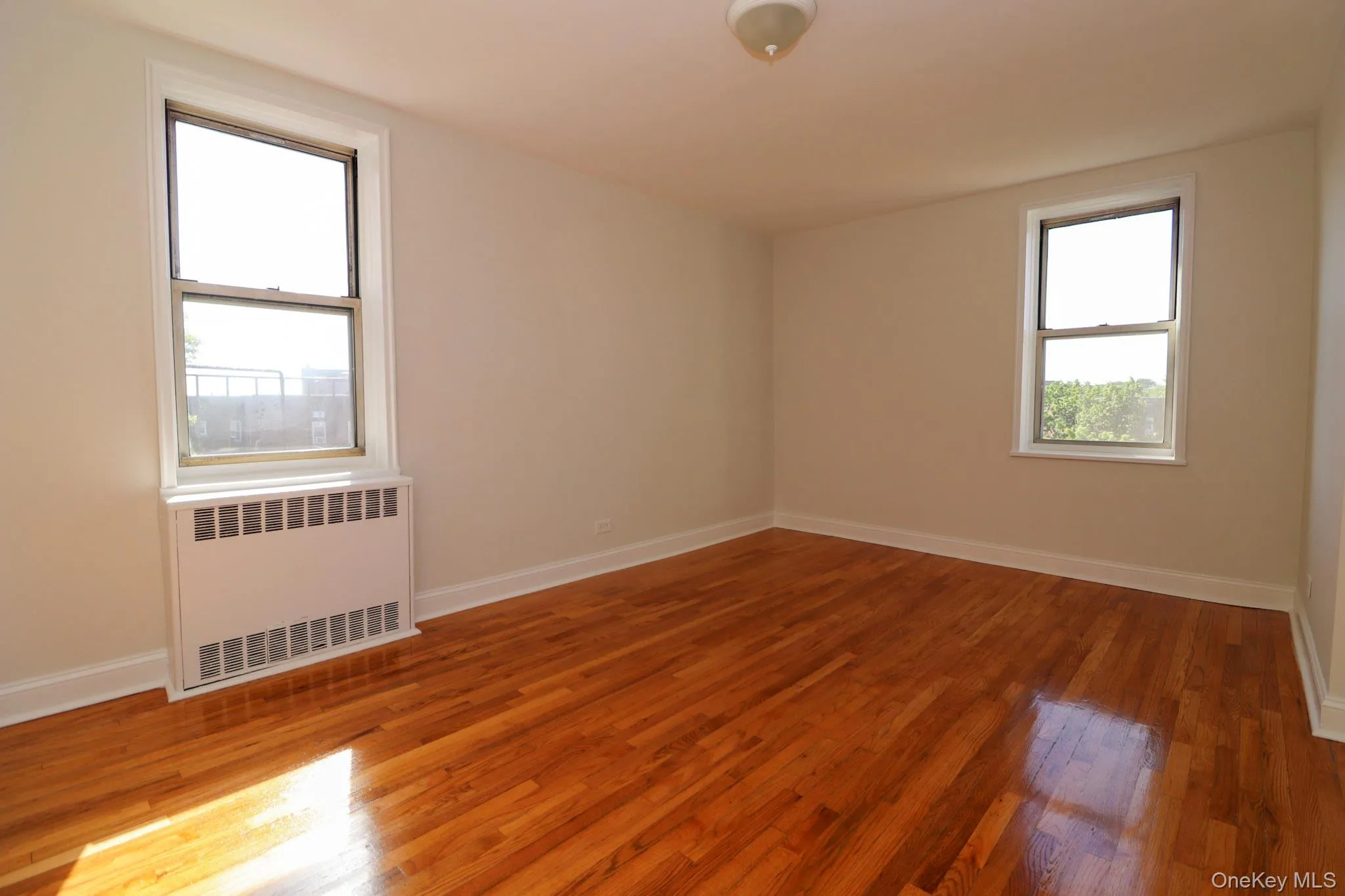 Unfurnished room featuring radiator heating unit and light wood-style floors Unfurnished room featuring radiator heating unit and light wood-style floors