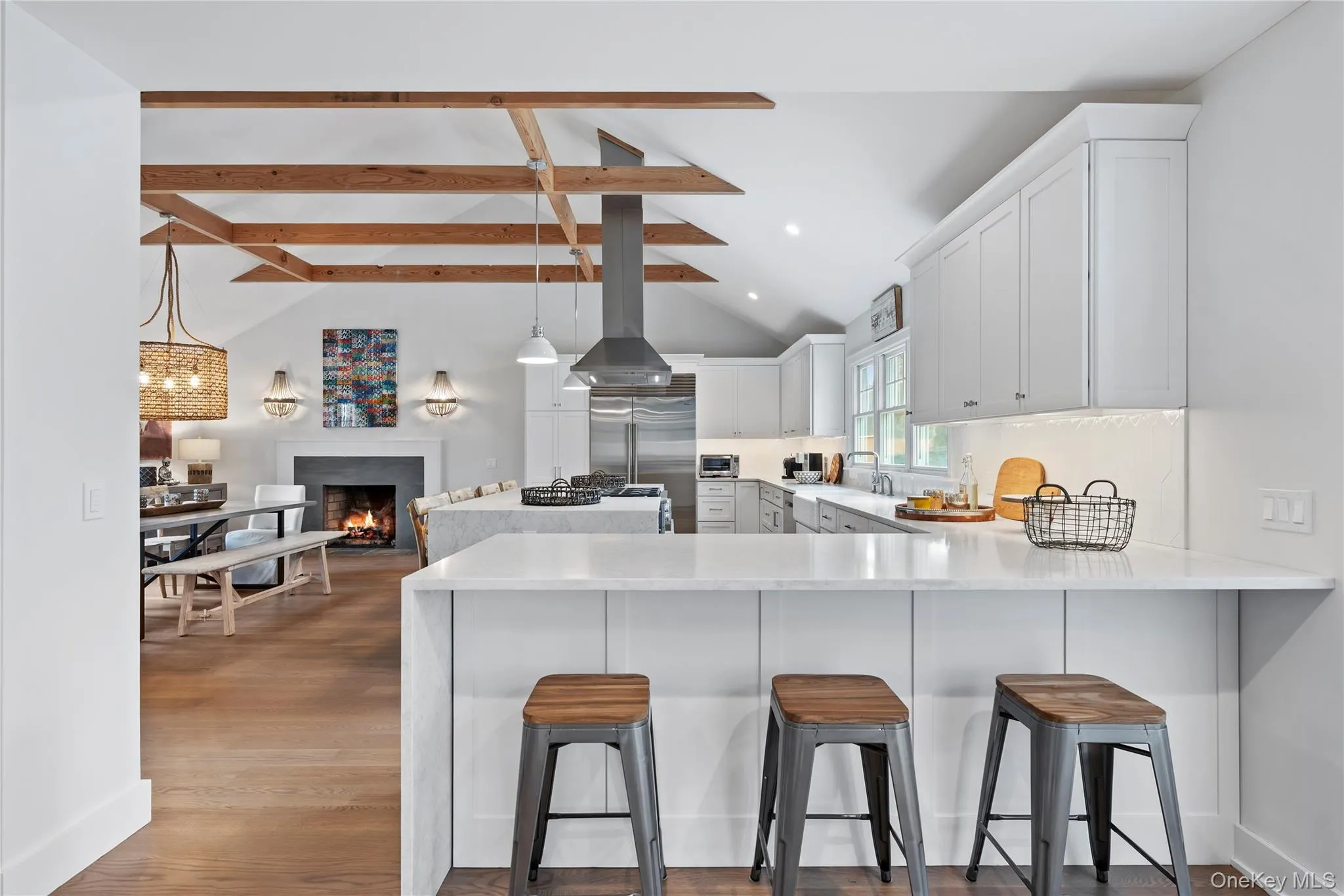 Kitchen with beam ceiling, a kitchen bar, a peninsula, light stone countertops, and high vaulted ceiling