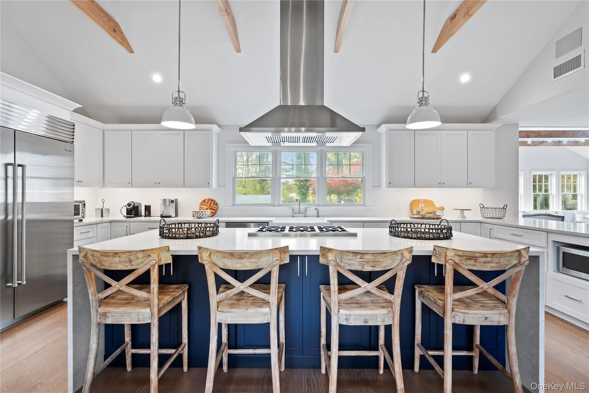 Kitchen with blue cabinetry, beamed ceiling, a kitchen island, white cabinetry, and range hood