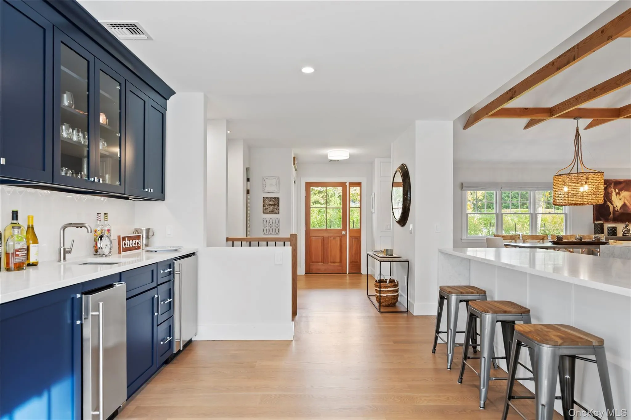 Indoor wet bar featuring light stone counters, light wood-style floors, glass insert cabinets, blue cabinets, and recessed lighting