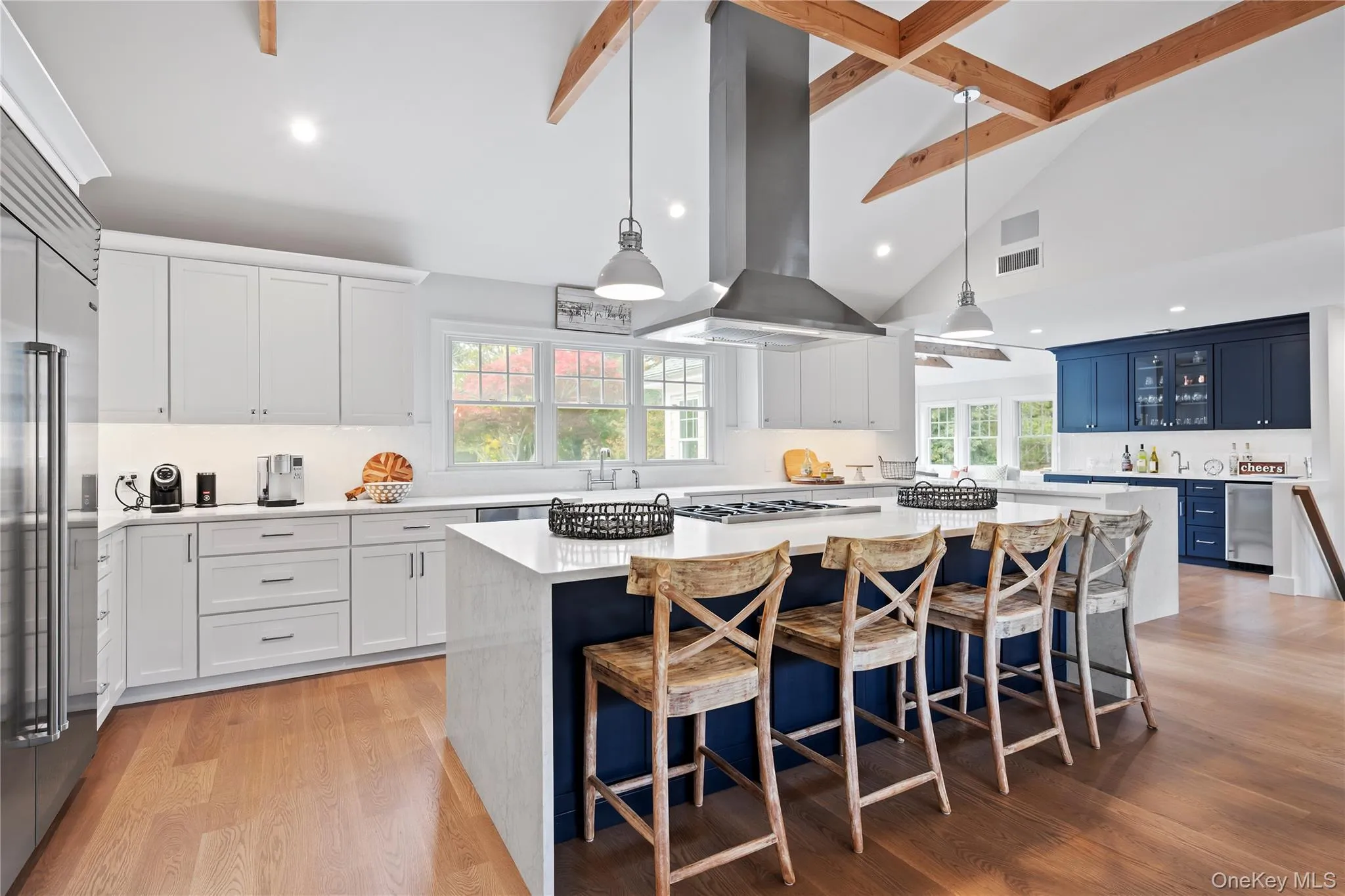 Kitchen featuring beamed ceiling, light stone counters, blue cabinetry, a kitchen island, and built in fridge