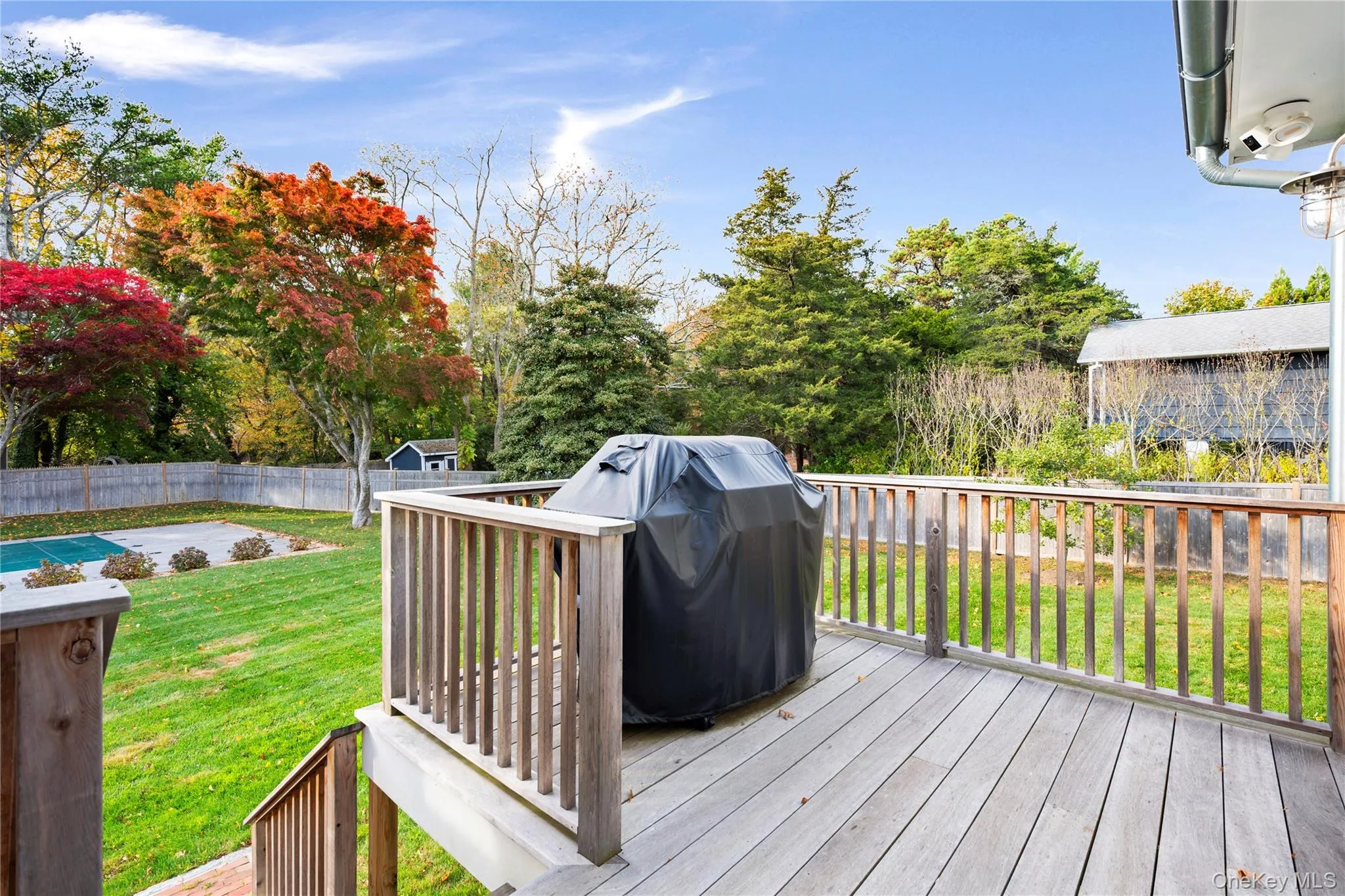 Wooden deck with grilling area, a fenced backyard, and a swimming pool