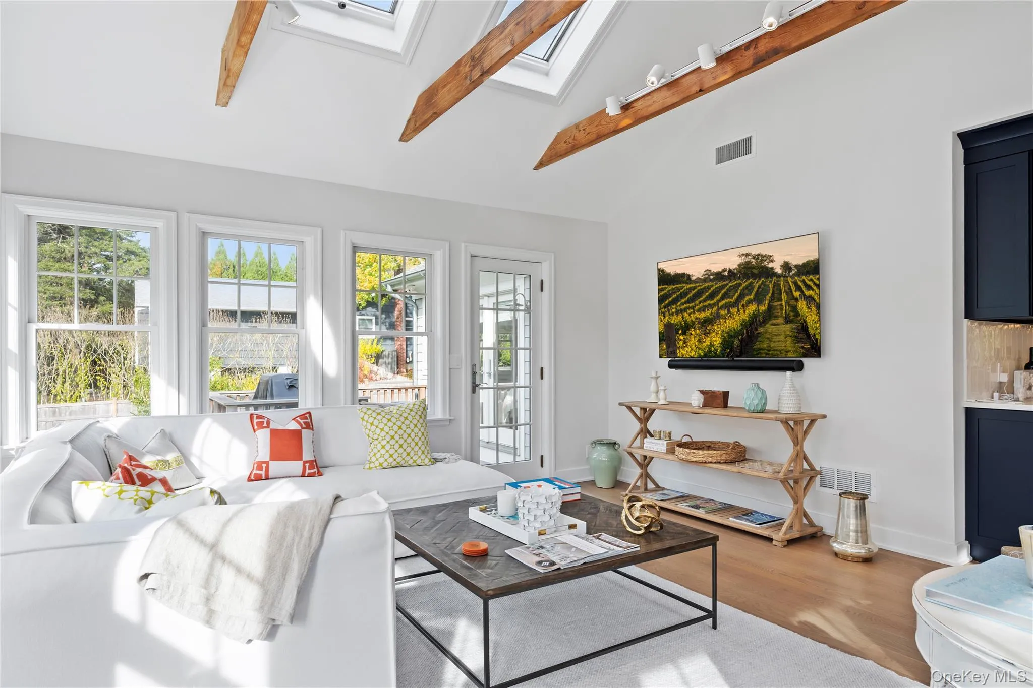 Living room with beamed ceiling, a skylight, high vaulted ceiling, and light wood-style floors