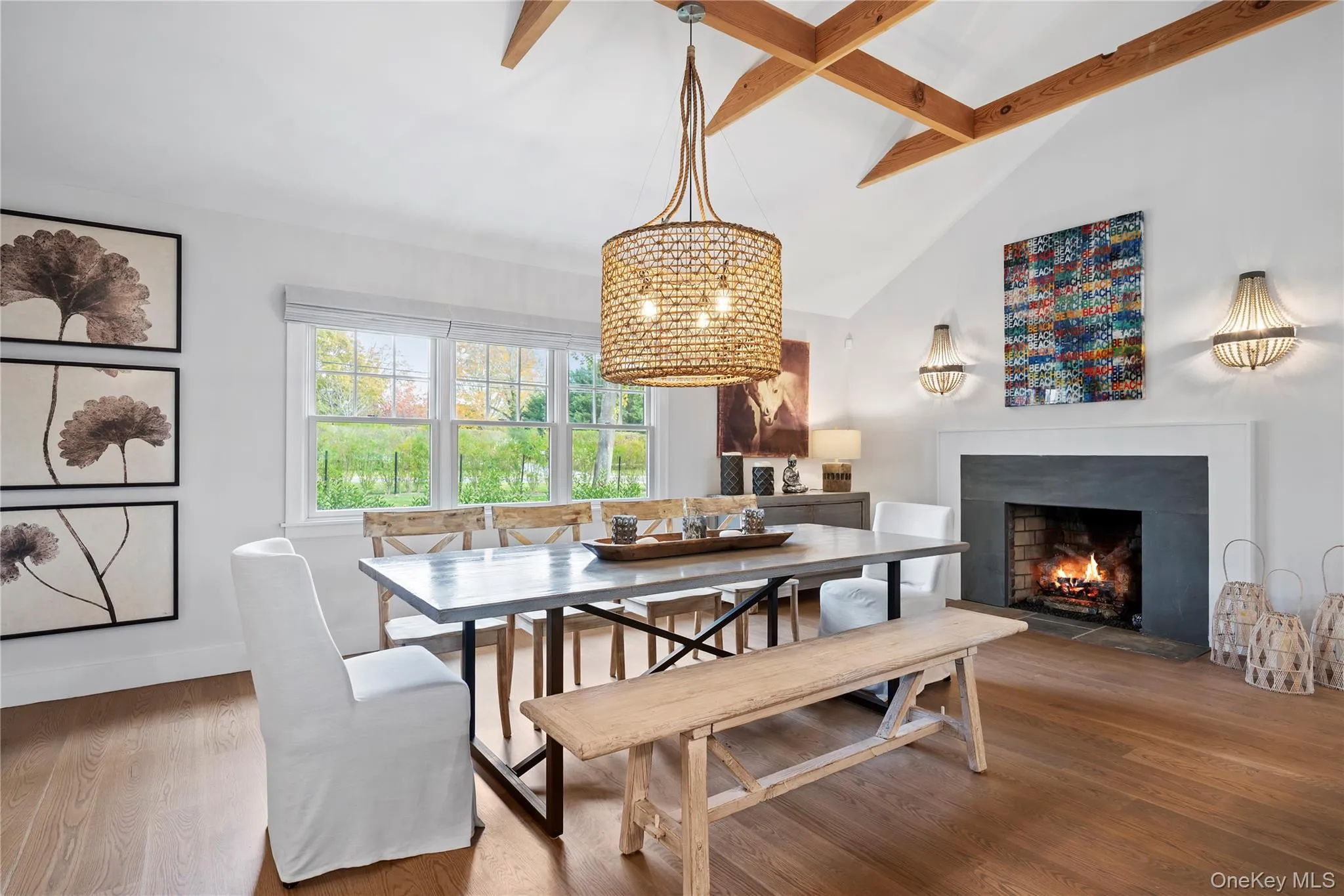Dining room with a fireplace with flush hearth, beam ceiling, wood finished floors, and high vaulted ceiling