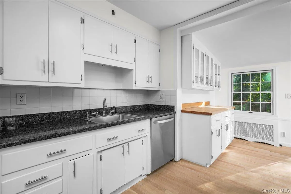 Kitchen with light wood-style flooring, radiator heating unit, and white cabinetry Kitchen with light wood-style flooring, radiator heating unit, and white cabinetry