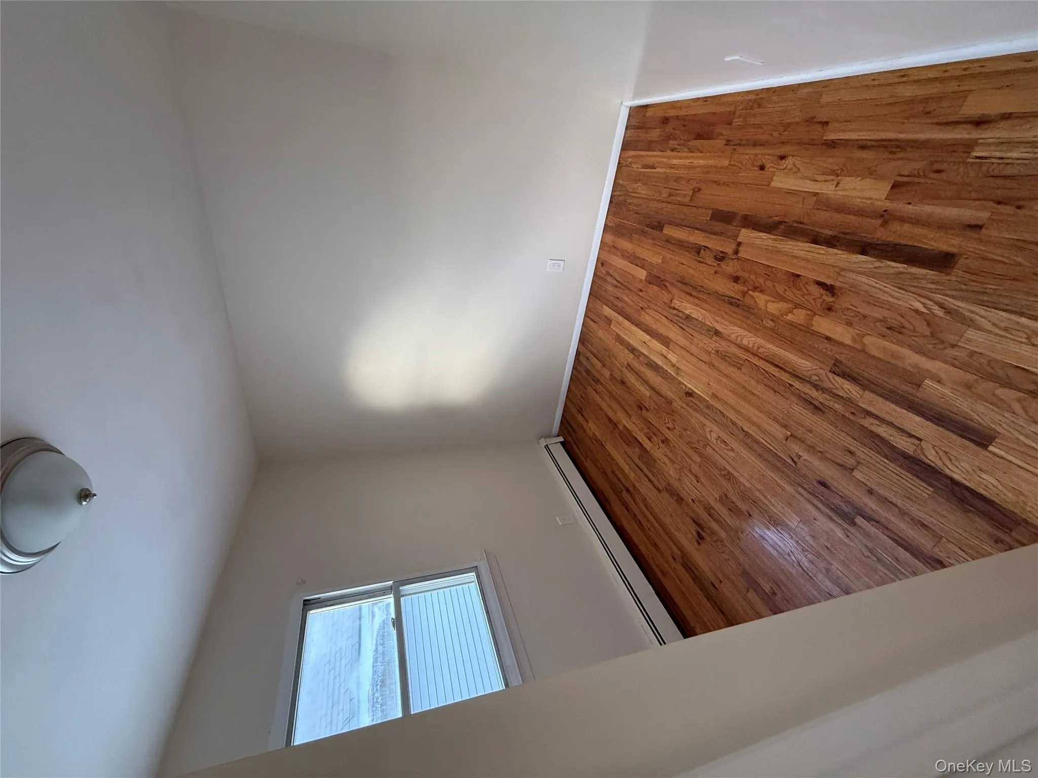 Spare room with wood finished floors and baseboard heating Spare room with wood finished floors and baseboard heating