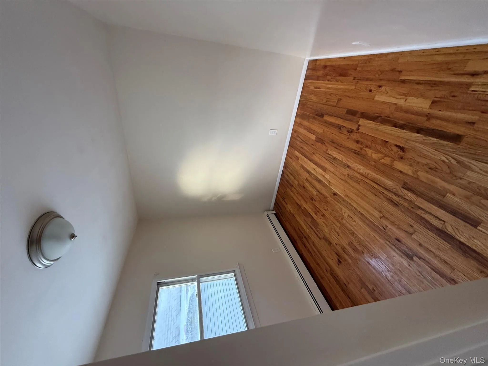 Empty room with wood finished floors and a baseboard heating unit Empty room with wood finished floors and a baseboard heating unit