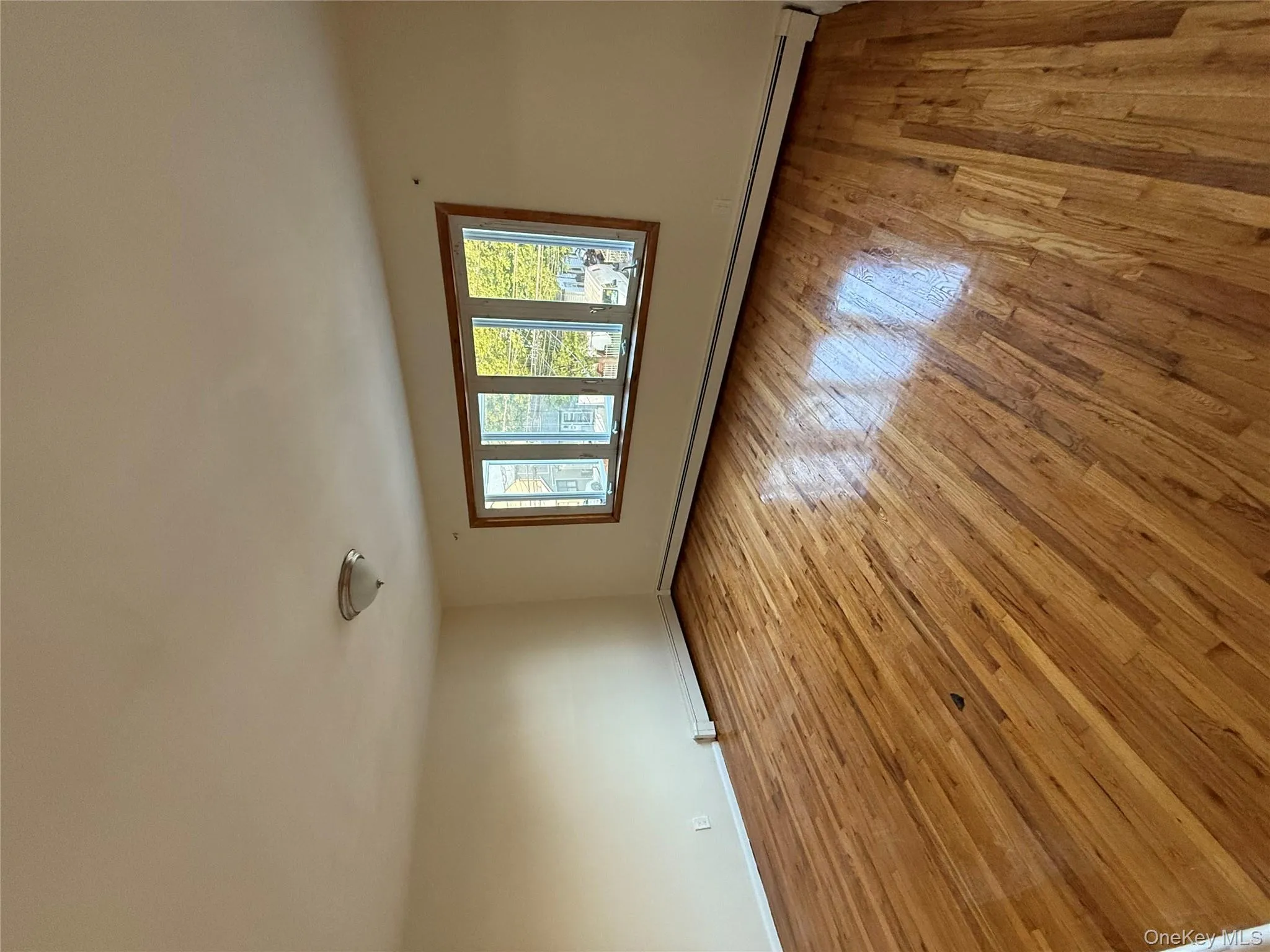Empty room with light wood-style flooring and a baseboard radiator Empty room with light wood-style flooring and a baseboard radiator