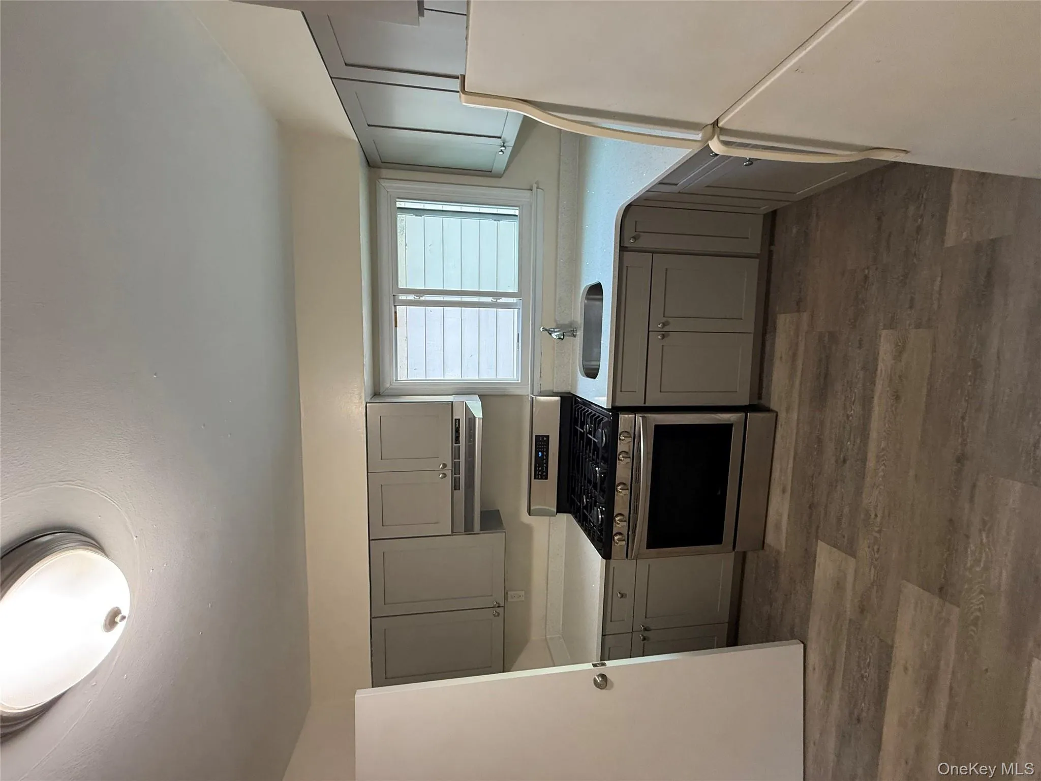 Kitchen with gray cabinetry, stove, refrigerator, and dark wood finished floors Kitchen with gray cabinetry, stove, refrigerator, and dark wood finished floors