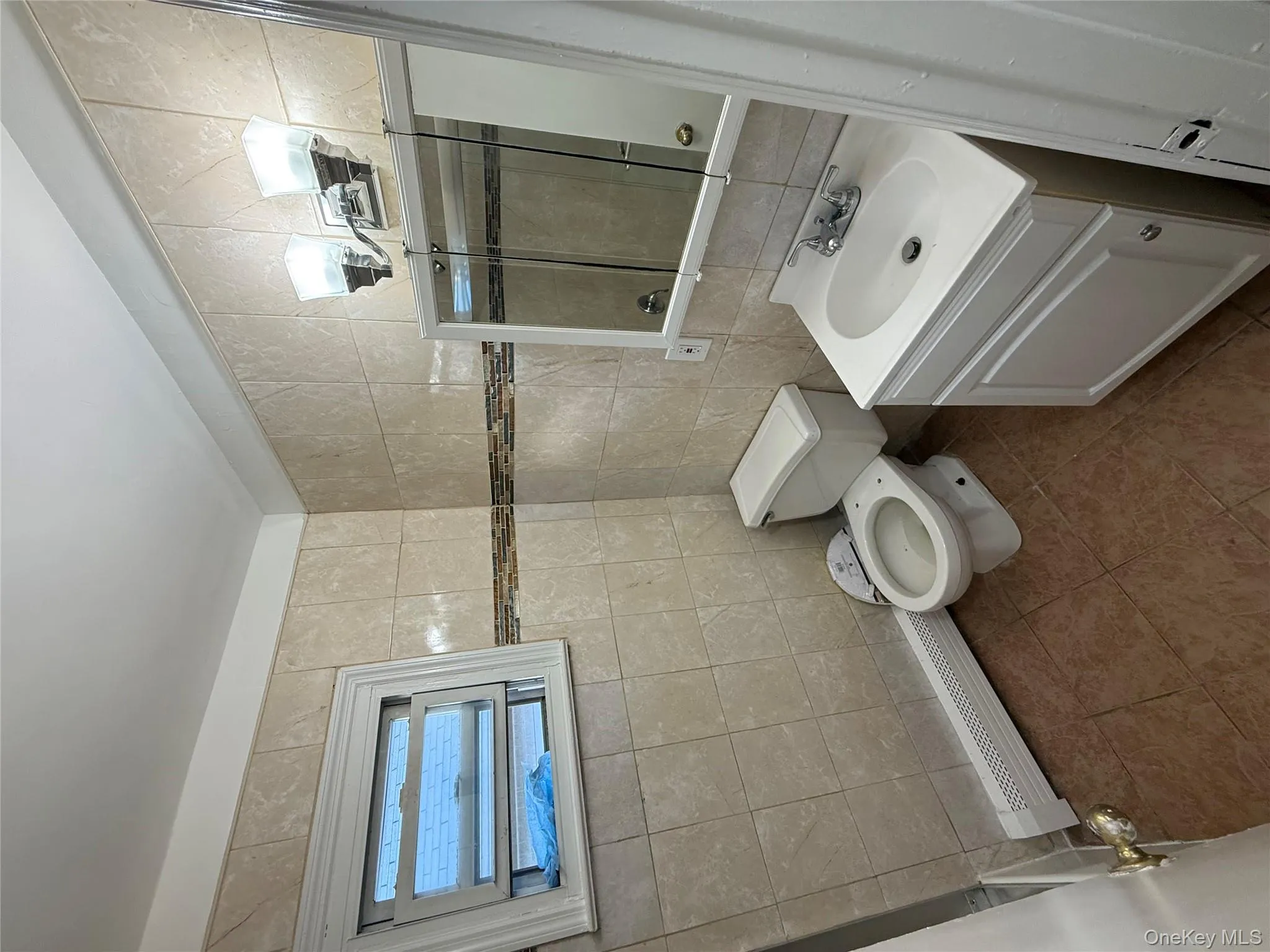 Full bath featuring tile walls, a baseboard heating unit, tile patterned floors, vanity, and a tile shower Full bath featuring tile walls, a baseboard heating unit, tile patterned floors, vanity, and a tile shower
