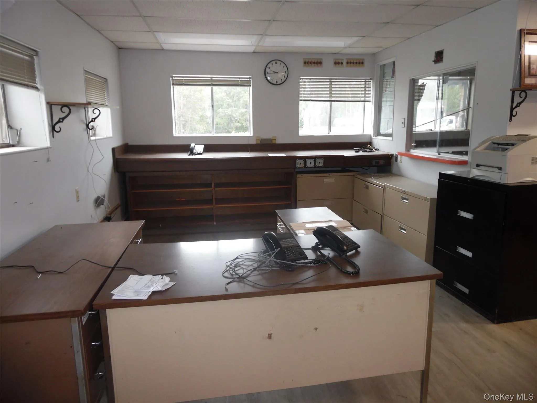 Kitchen featuring healthy amount of natural light, a drop ceiling, light wood-style floors, and dark countertops Kitchen featuring healthy amount of natural light, a drop ceiling, light wood-style floors, and dark countertops