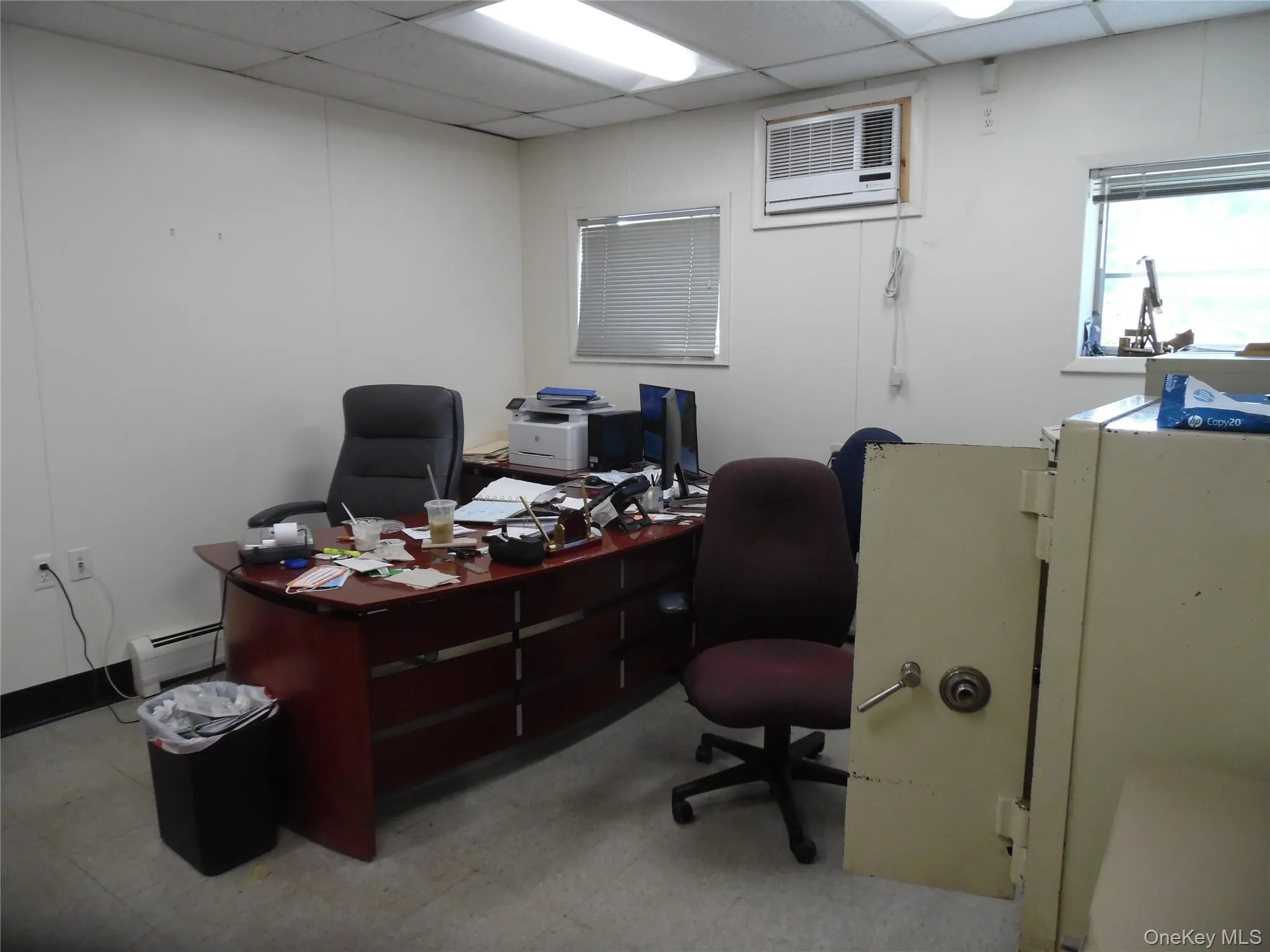 Office space featuring a paneled ceiling, a baseboard radiator, light floors, and a wall mounted air conditioner Office space featuring a paneled ceiling, a baseboard radiator, light floors, and a wall mounted air conditioner
