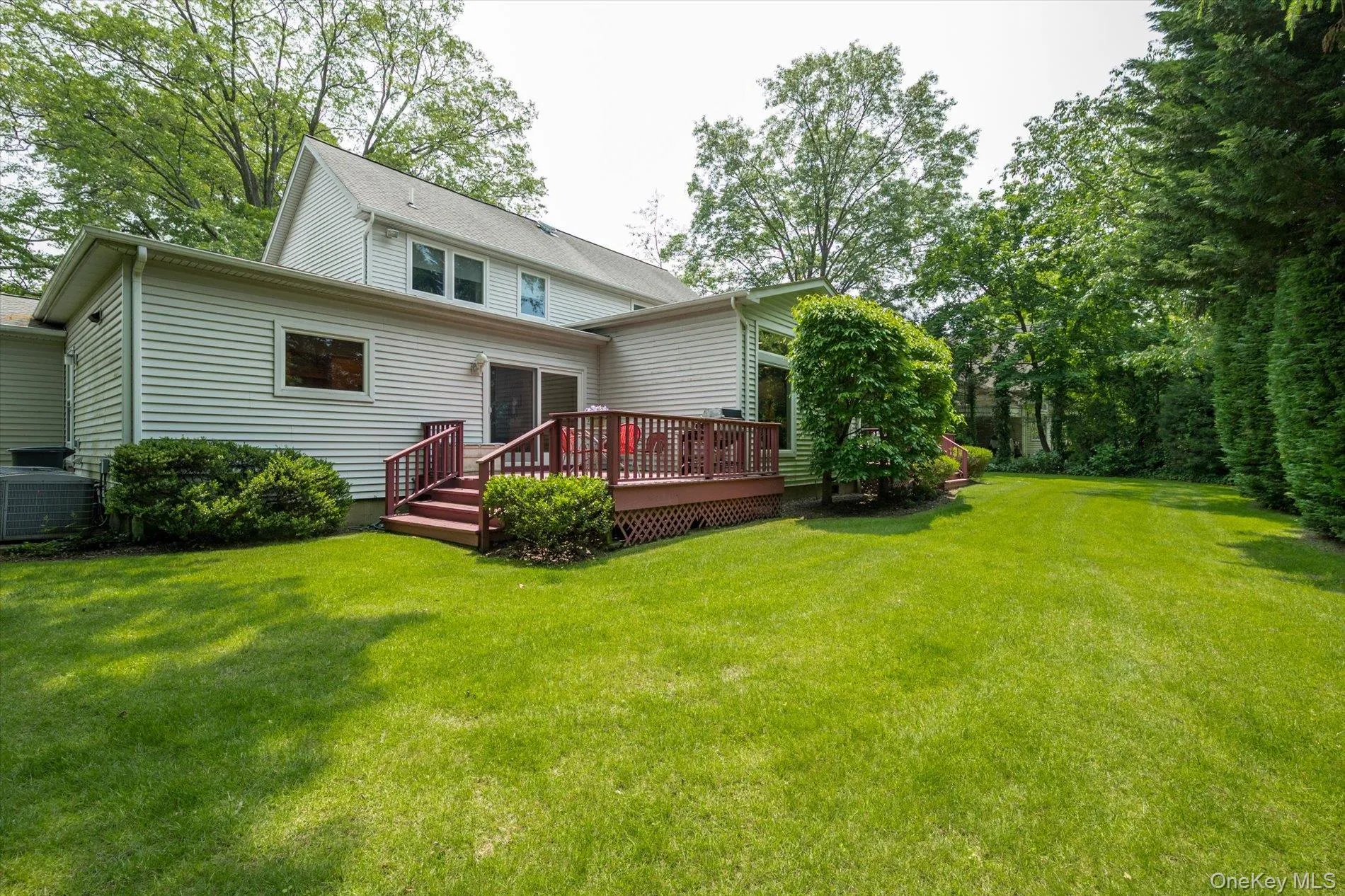 Back of house with a wooden deck and a lawn Back of house with a wooden deck and a lawn