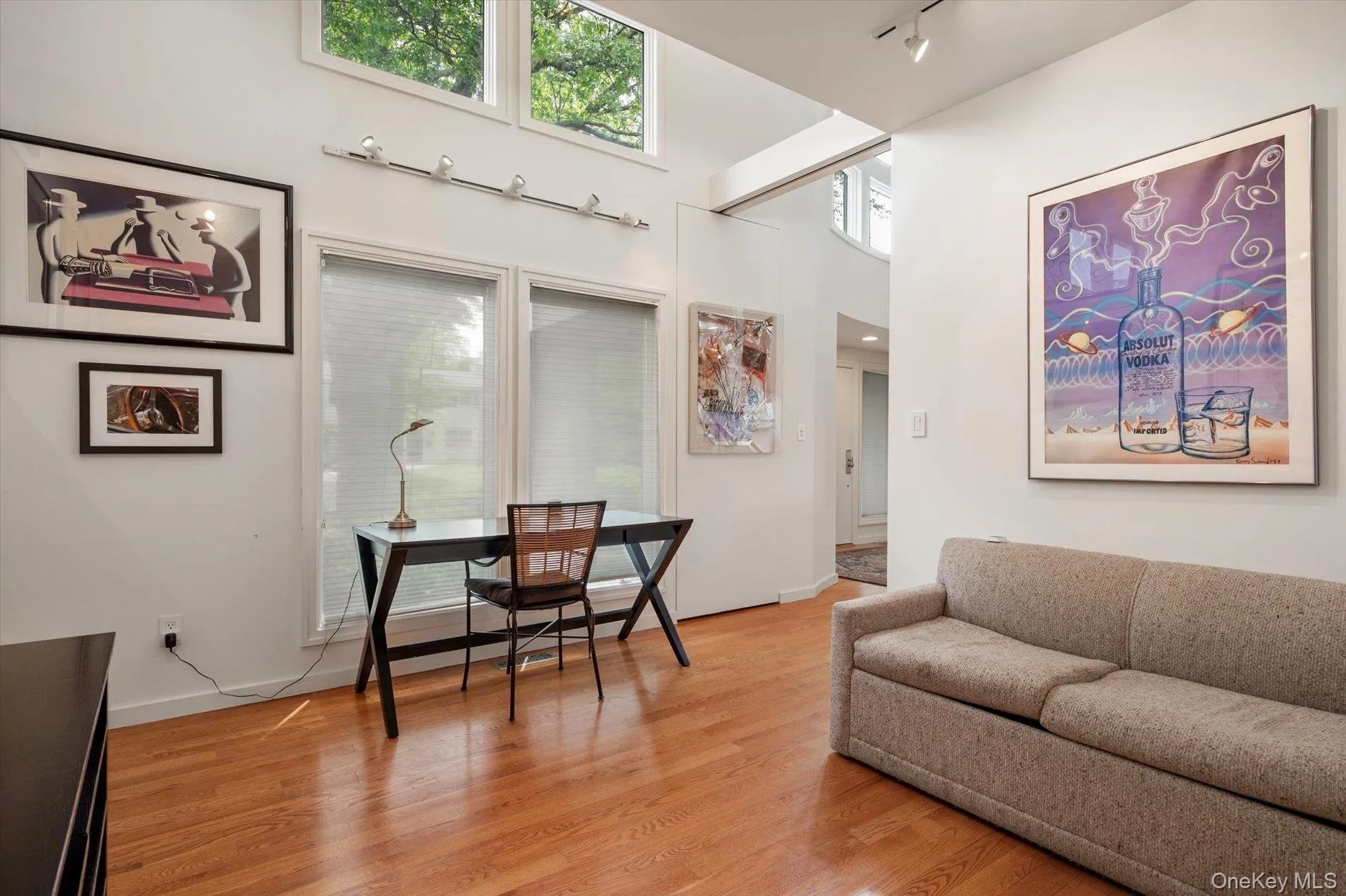Living area featuring light wood-type flooring, a high ceiling, and rail lighting Living area featuring light wood-type flooring, a high ceiling, and rail lighting