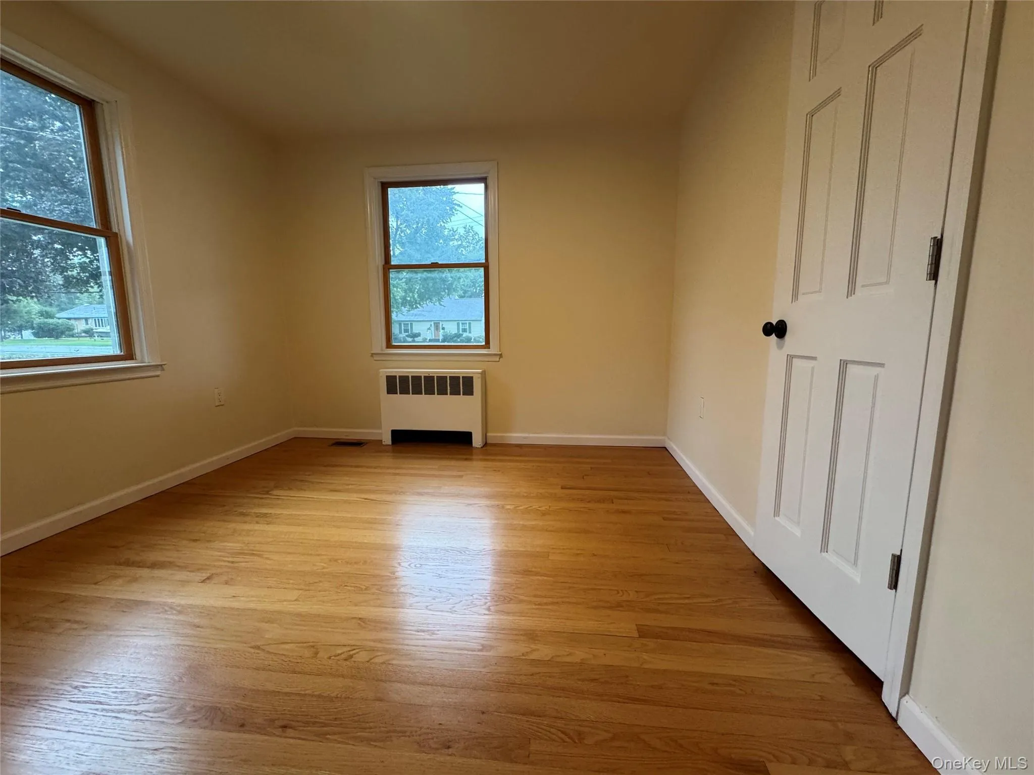 Spare room featuring radiator and light wood finished floors Spare room featuring radiator and light wood finished floors