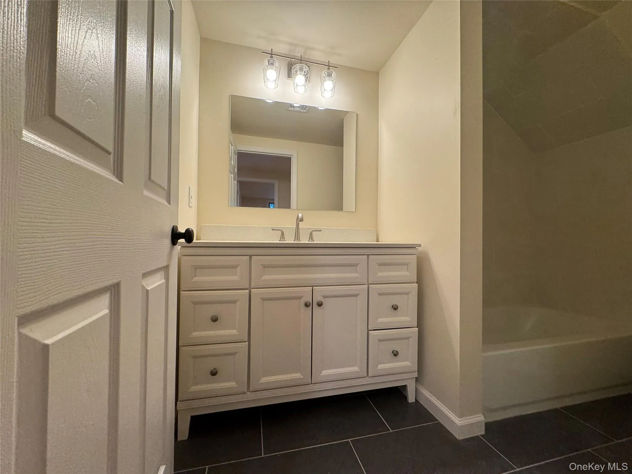 Full bathroom featuring vanity, dark tile patterned floors, and shower combination Full bathroom featuring vanity, dark tile patterned floors, and shower combination