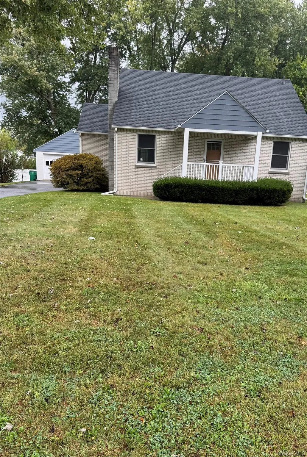 Ranch-style house featuring a front lawn, a chimney, a garage, a porch, and roof with shingles Ranch-style house featuring a front lawn, a chimney, a garage, a porch, and roof with shingles