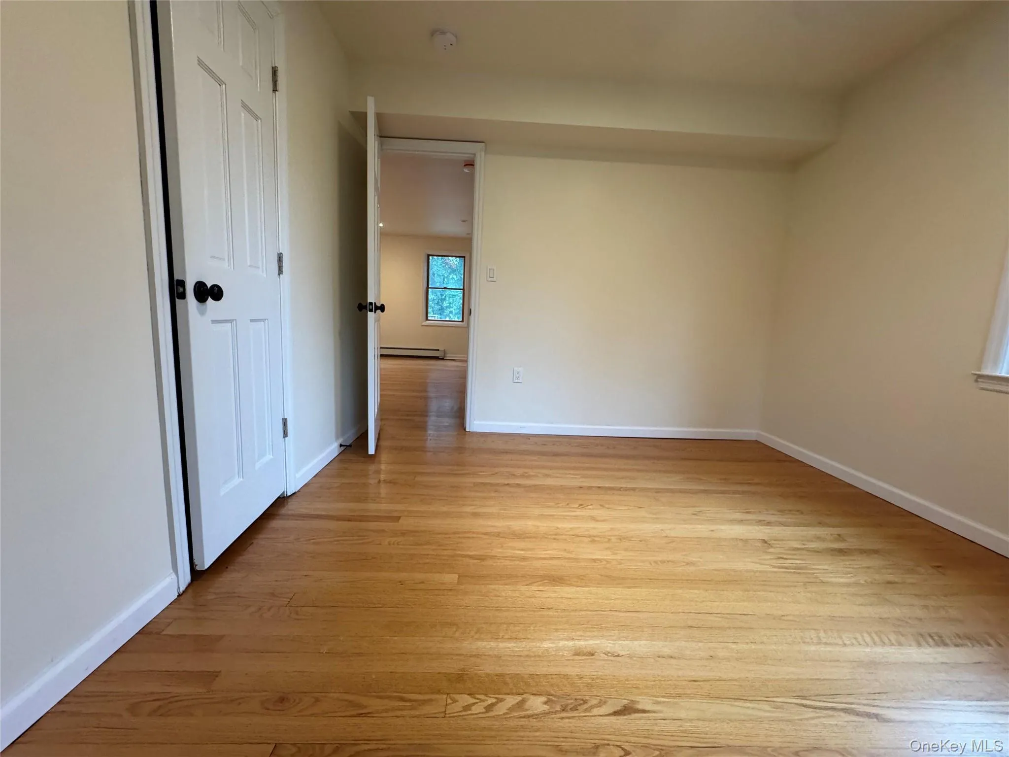 Spare room with light wood-style flooring and a baseboard heating unit Spare room with light wood-style flooring and a baseboard heating unit