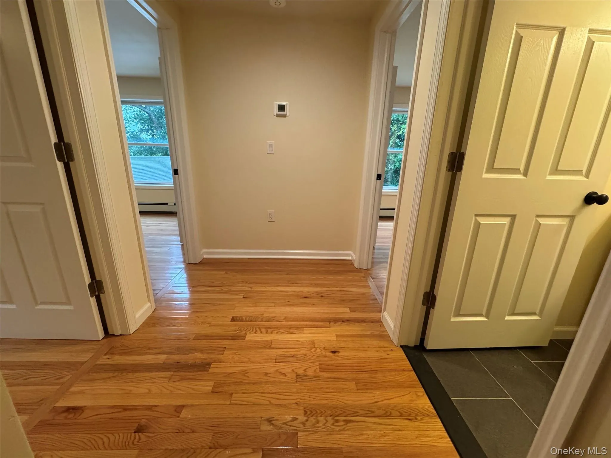 Hall with light wood-type flooring and a baseboard radiator Hall with light wood-type flooring and a baseboard radiator