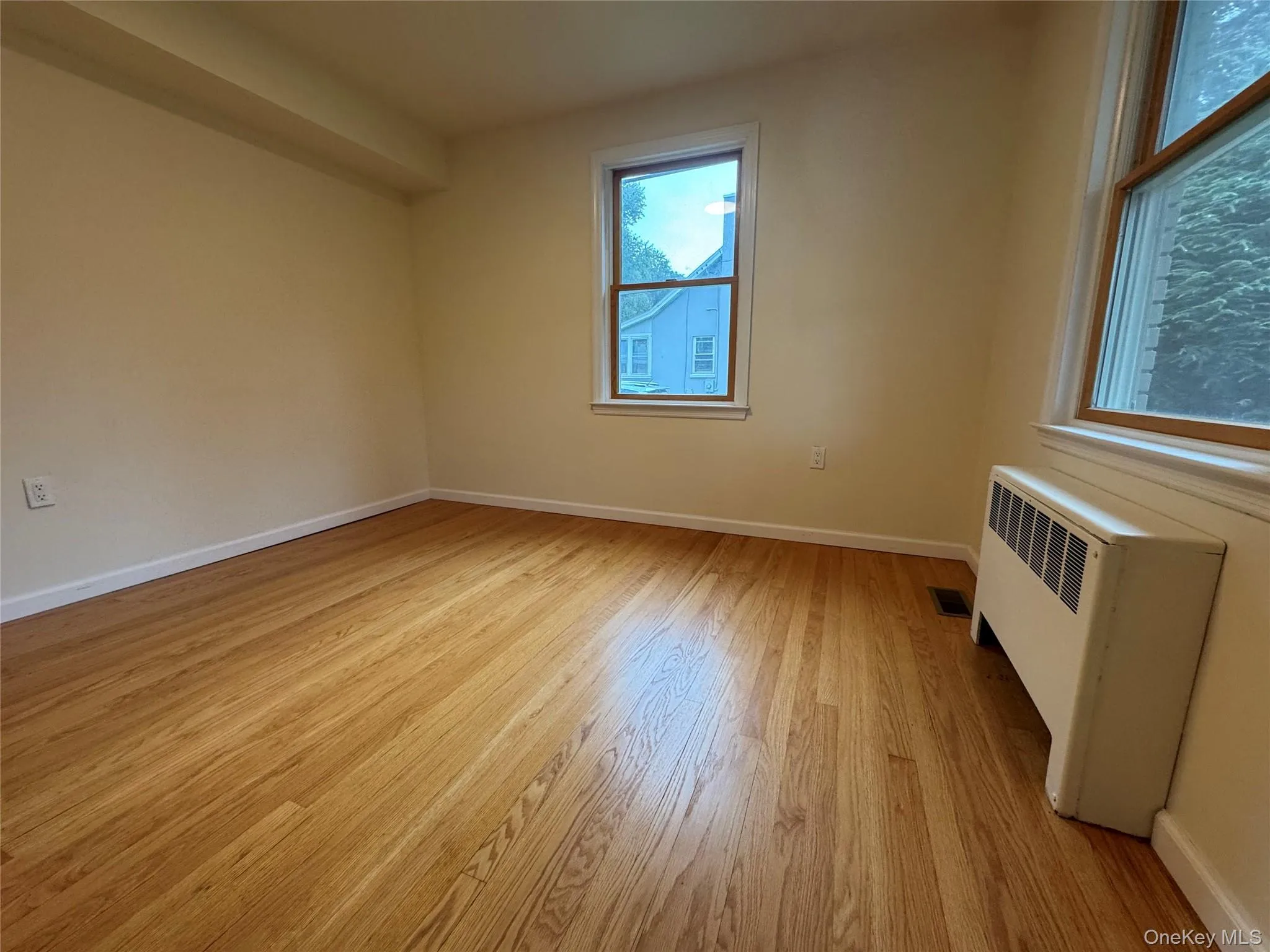 Empty room featuring radiator heating unit and light wood-type flooring Empty room featuring radiator heating unit and light wood-type flooring