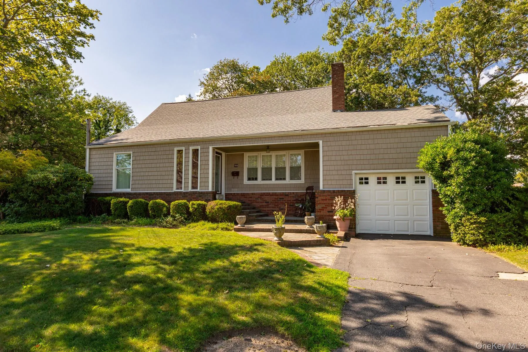 Single story home with a front lawn, a chimney, driveway, a garage, and a shingled roof Single story home with a front lawn, a chimney, driveway, a garage, and a shingled roof