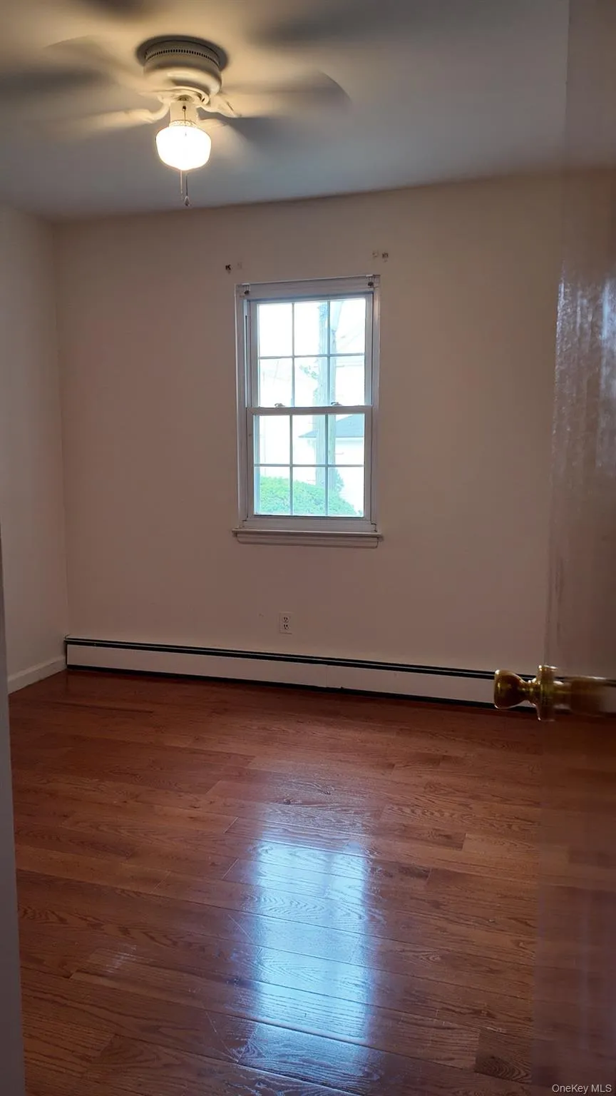 Unfurnished room featuring dark wood-style flooring and a baseboard radiator Unfurnished room featuring dark wood-style flooring and a baseboard radiator