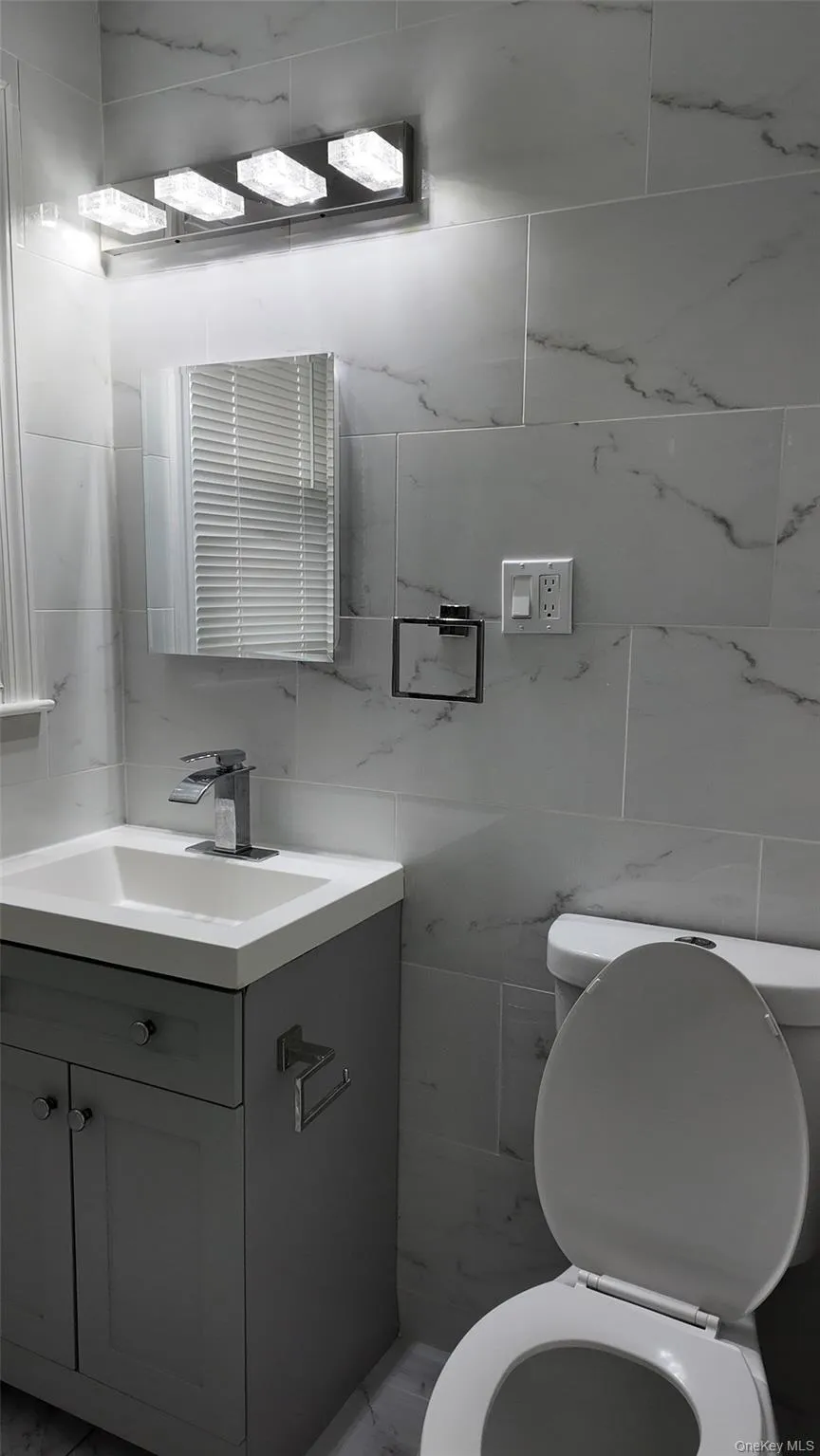 Bathroom with vanity, tile walls, and tasteful backsplash Bathroom with vanity, tile walls, and tasteful backsplash