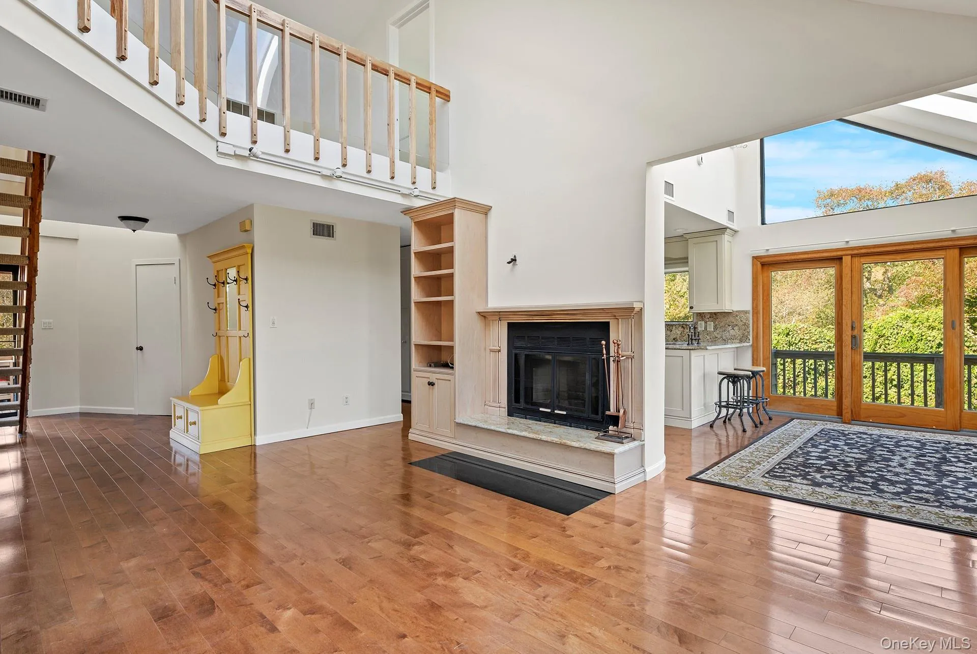 Unfurnished living room with a high ceiling, a high end fireplace, and wood finished floors Unfurnished living room with a high ceiling, a high end fireplace, and wood finished floors