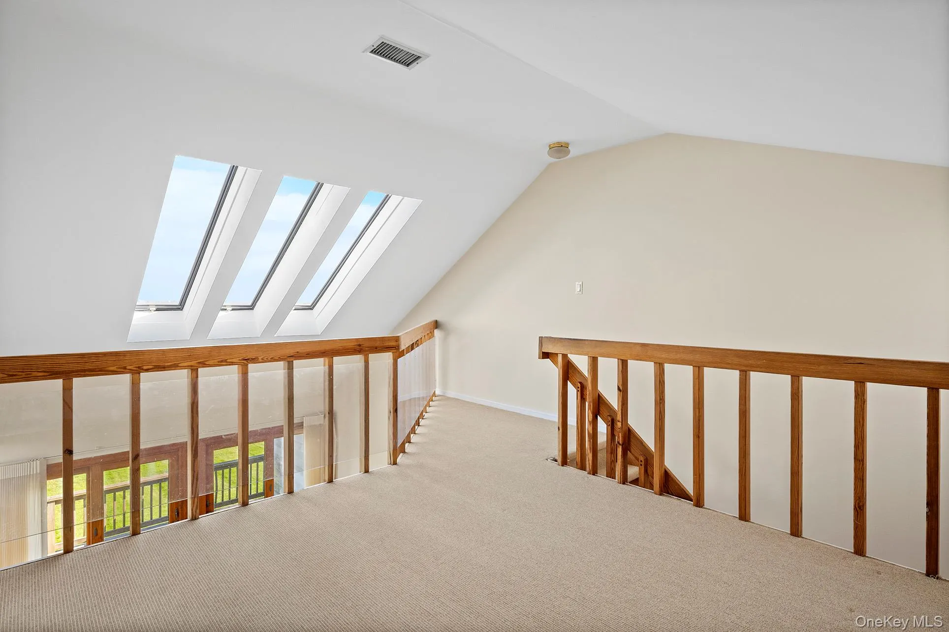 Hallway featuring plenty of natural light, lofted ceiling, and a skylight. Hallway featuring plenty of natural light, lofted ceiling, and a skylight.