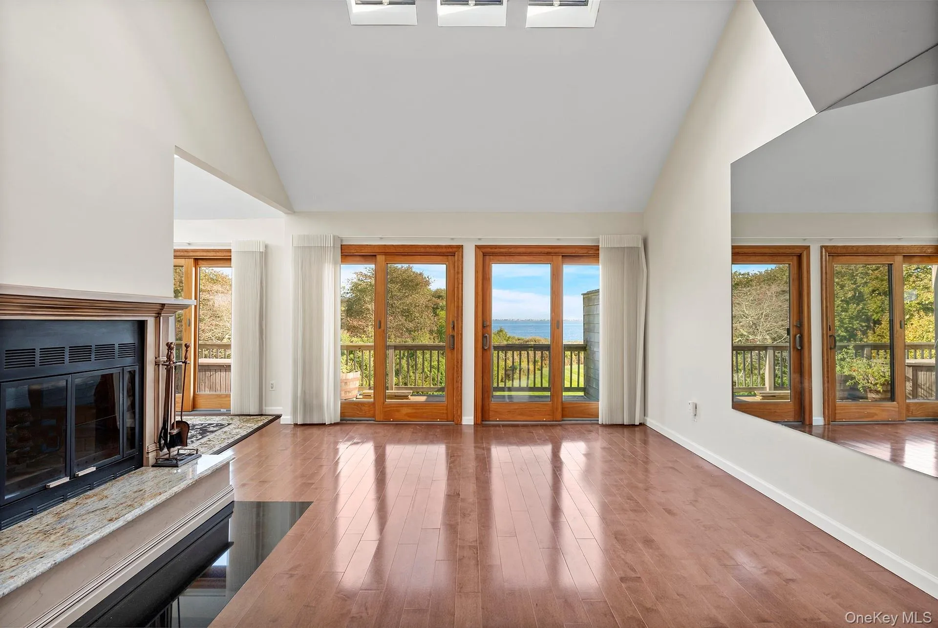 Unfurnished living room with high vaulted ceiling, wood finished floors, and a glass covered fireplace Unfurnished living room with high vaulted ceiling, wood finished floors, and a glass covered fireplace
