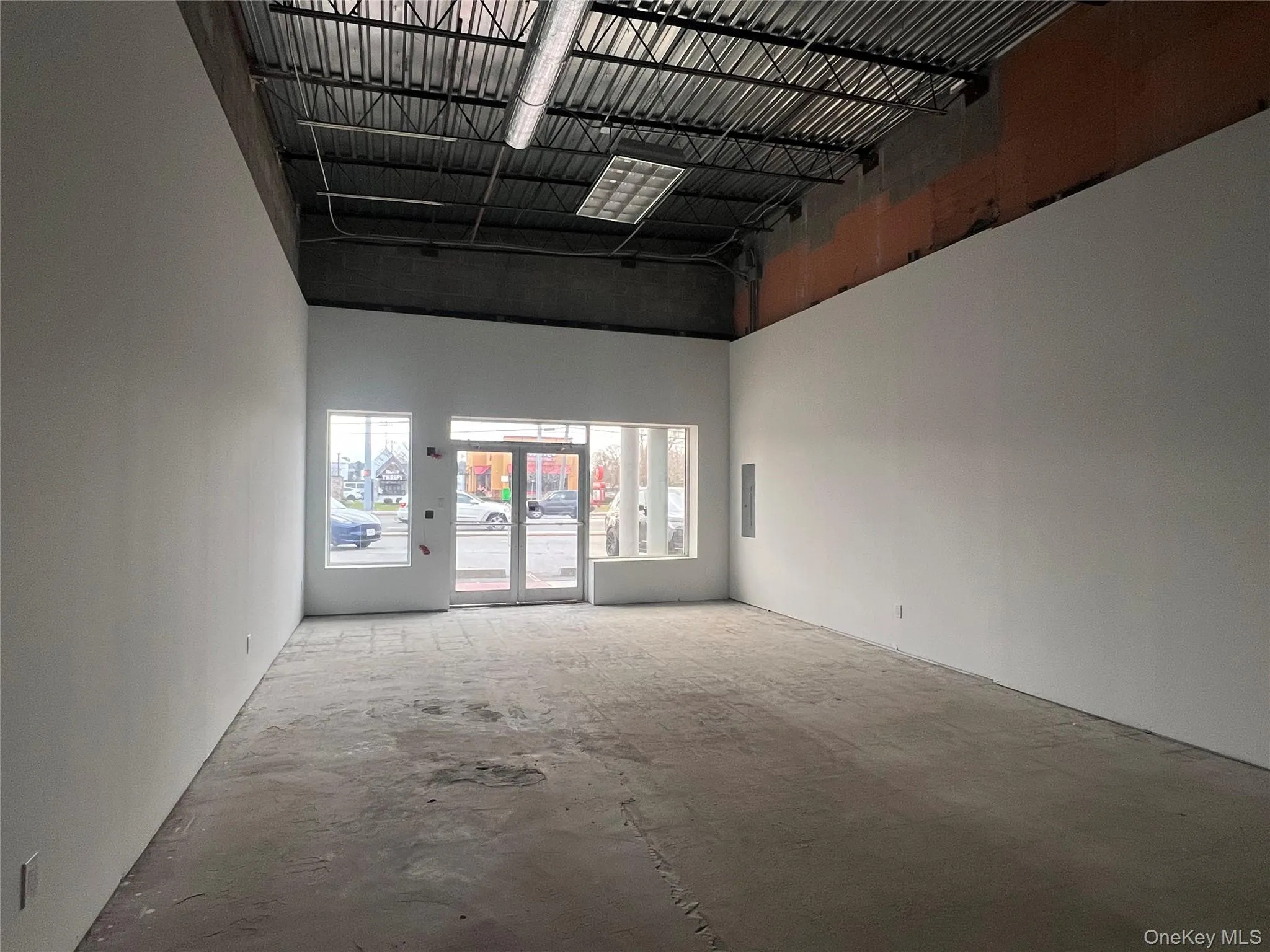 Spare room with a high ceiling, unfinished concrete flooring, and electric panel Spare room with a high ceiling, unfinished concrete flooring, and electric panel