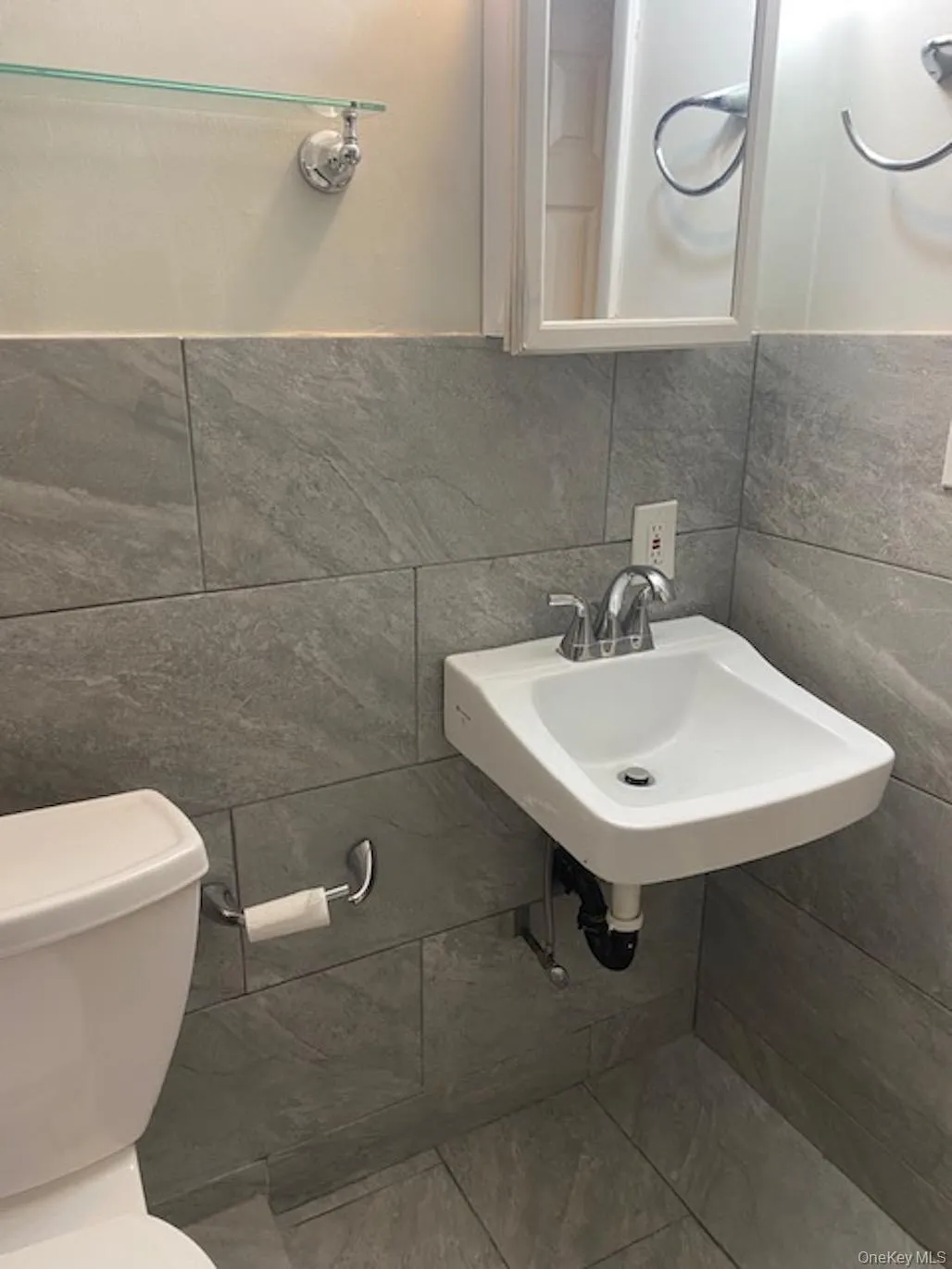 Half bath featuring a sink, tile walls, and toilet Half bath featuring a sink, tile walls, and toilet