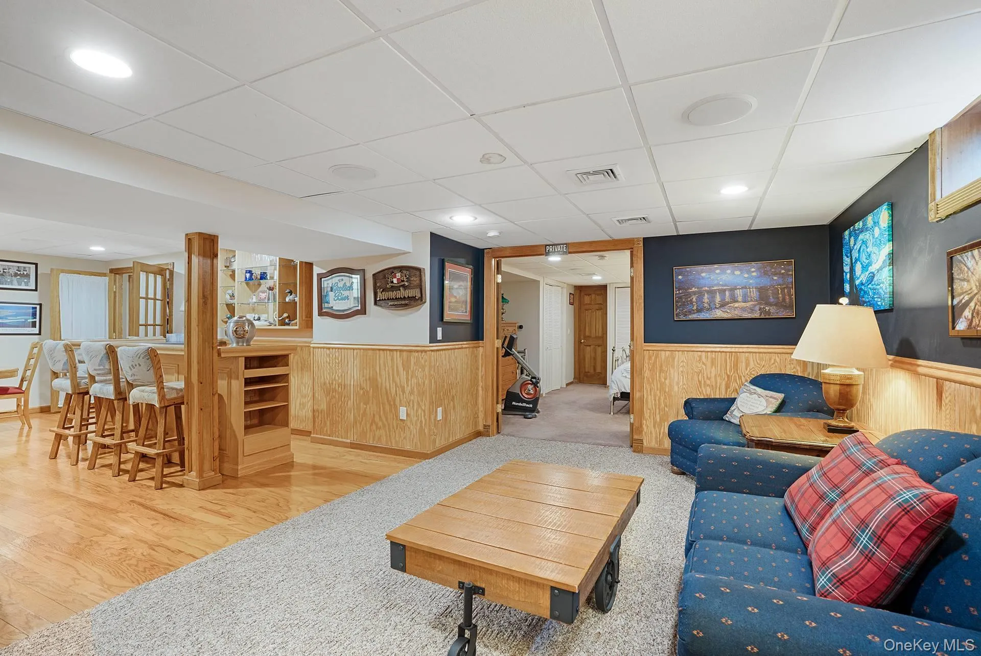 Living area featuring a paneled ceiling, wainscoting, wooden walls, recessed lighting, and carpet floors Living area featuring a paneled ceiling, wainscoting, wooden walls, recessed lighting, and carpet floors