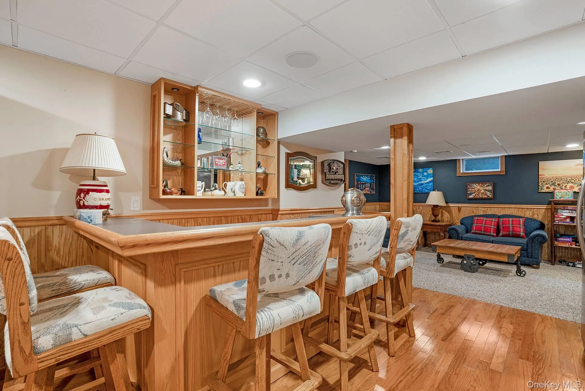 Indoor dry bar featuring a wainscoted wall, a paneled ceiling, light wood-type flooring, wooden walls, and open shelves Indoor dry bar featuring a wainscoted wall, a paneled ceiling, light wood-type flooring, wooden walls, and open shelves