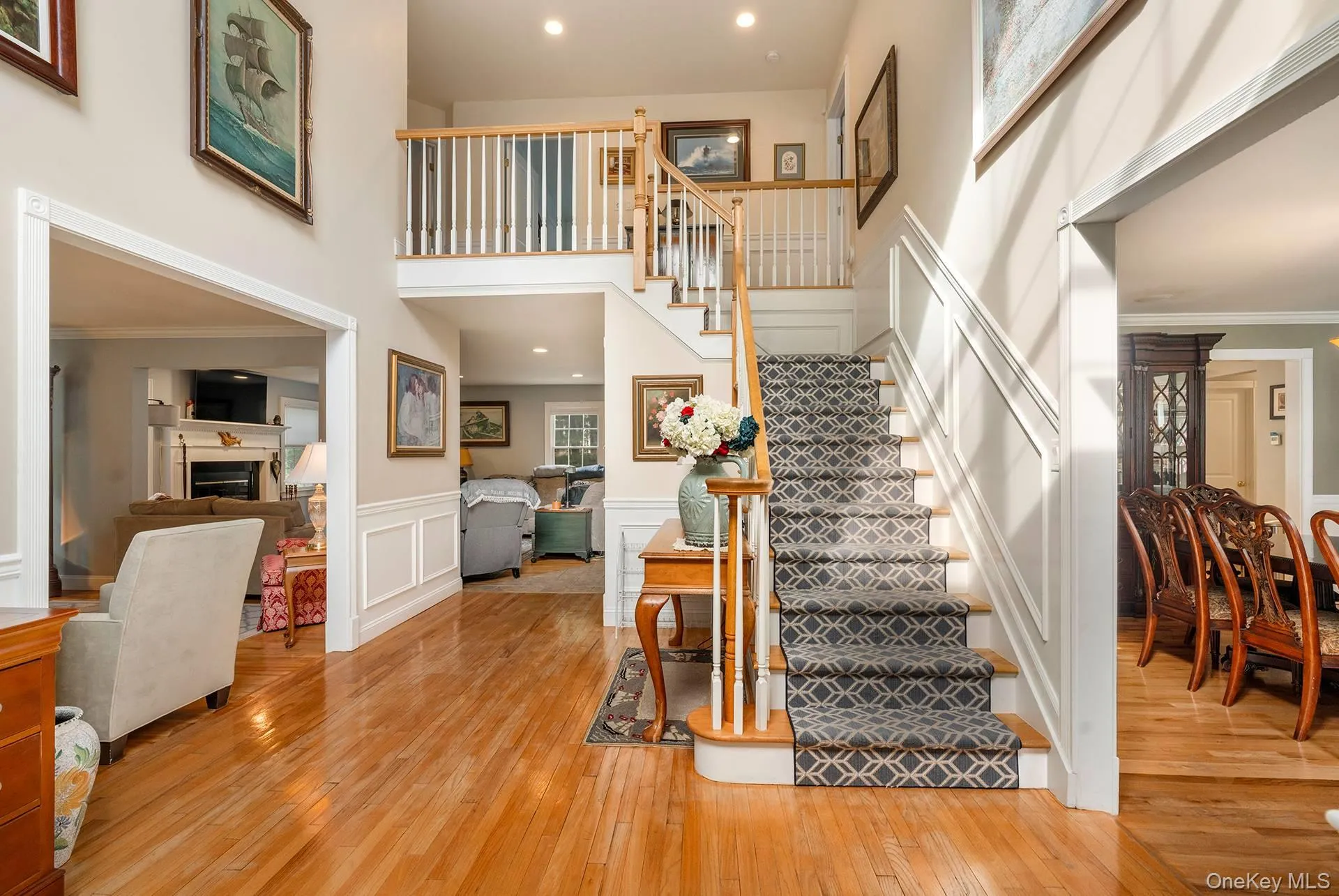 Staircase featuring a towering ceiling, a fireplace, hardwood / wood-style floors, a decorative wall, and recessed lighting Staircase featuring a towering ceiling, a fireplace, hardwood / wood-style floors, a decorative wall, and recessed lighting