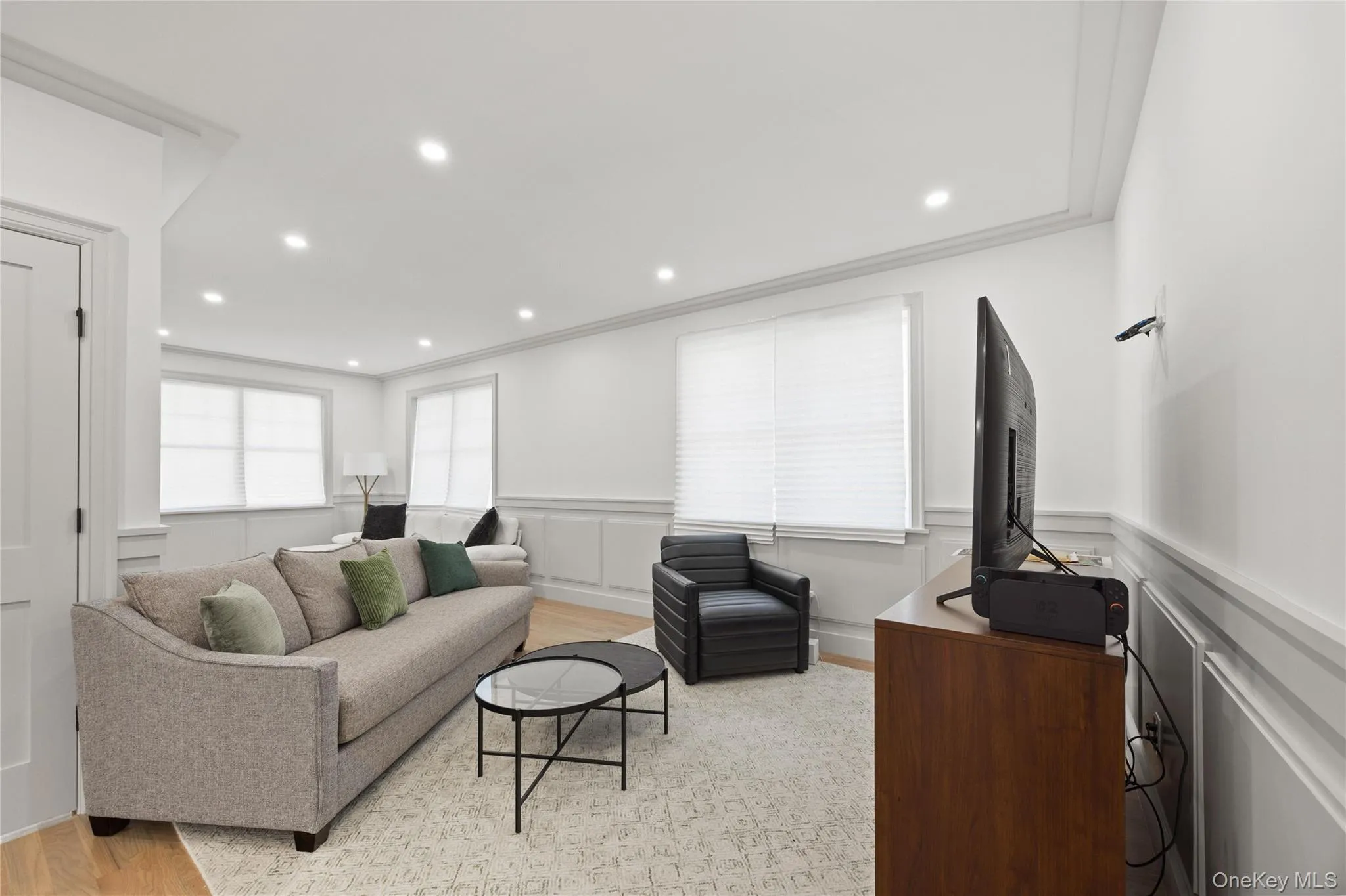 Living area with light wood finished floors, recessed lighting, a decorative wall, crown molding, and wainscoting Living area with light wood finished floors, recessed lighting, a decorative wall, crown molding, and wainscoting