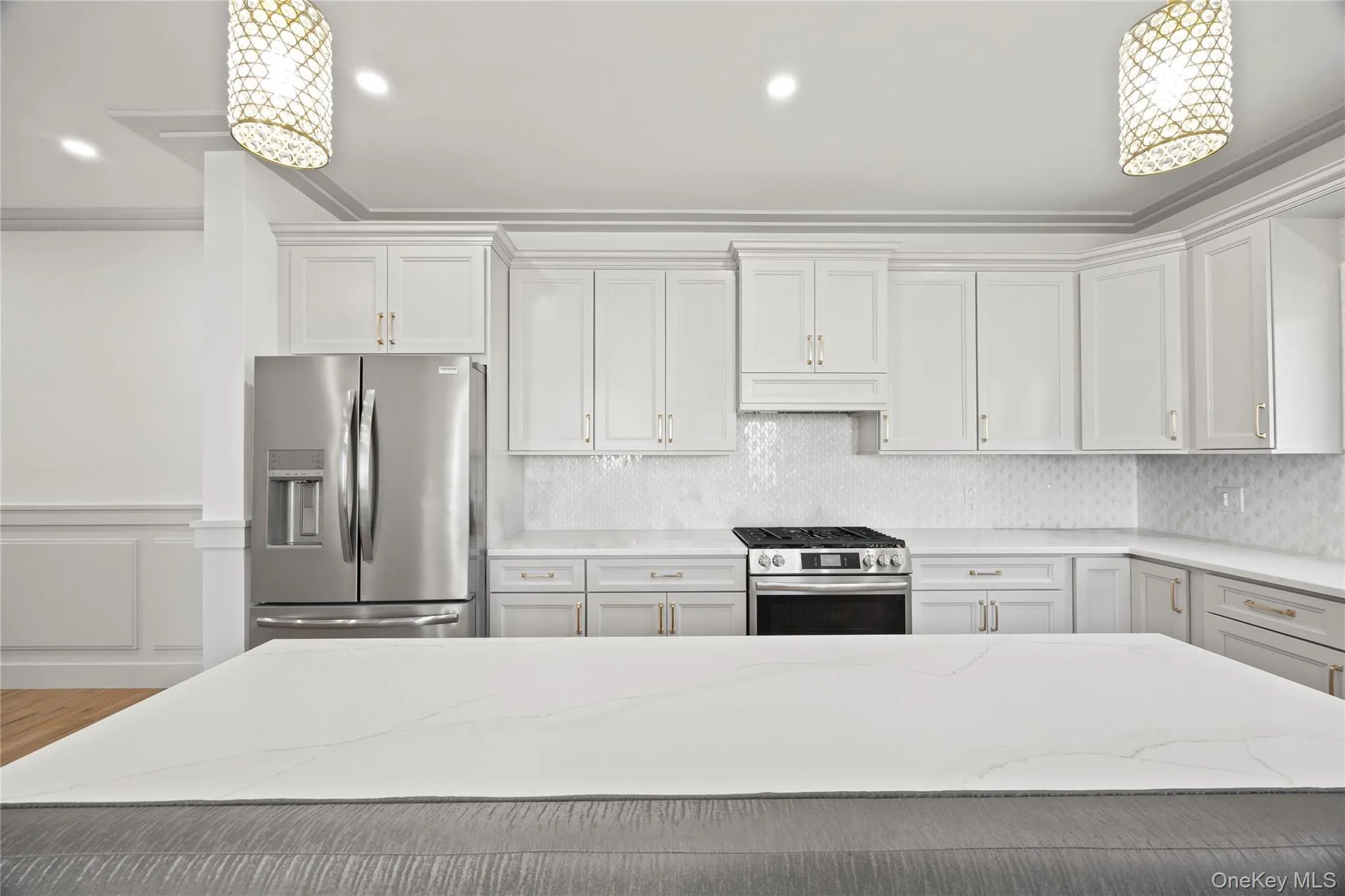 Kitchen with decorative light fixtures, appliances with stainless steel finishes, light stone counters, backsplash, and crown molding Kitchen with decorative light fixtures, appliances with stainless steel finishes, light stone counters, backsplash, and crown molding