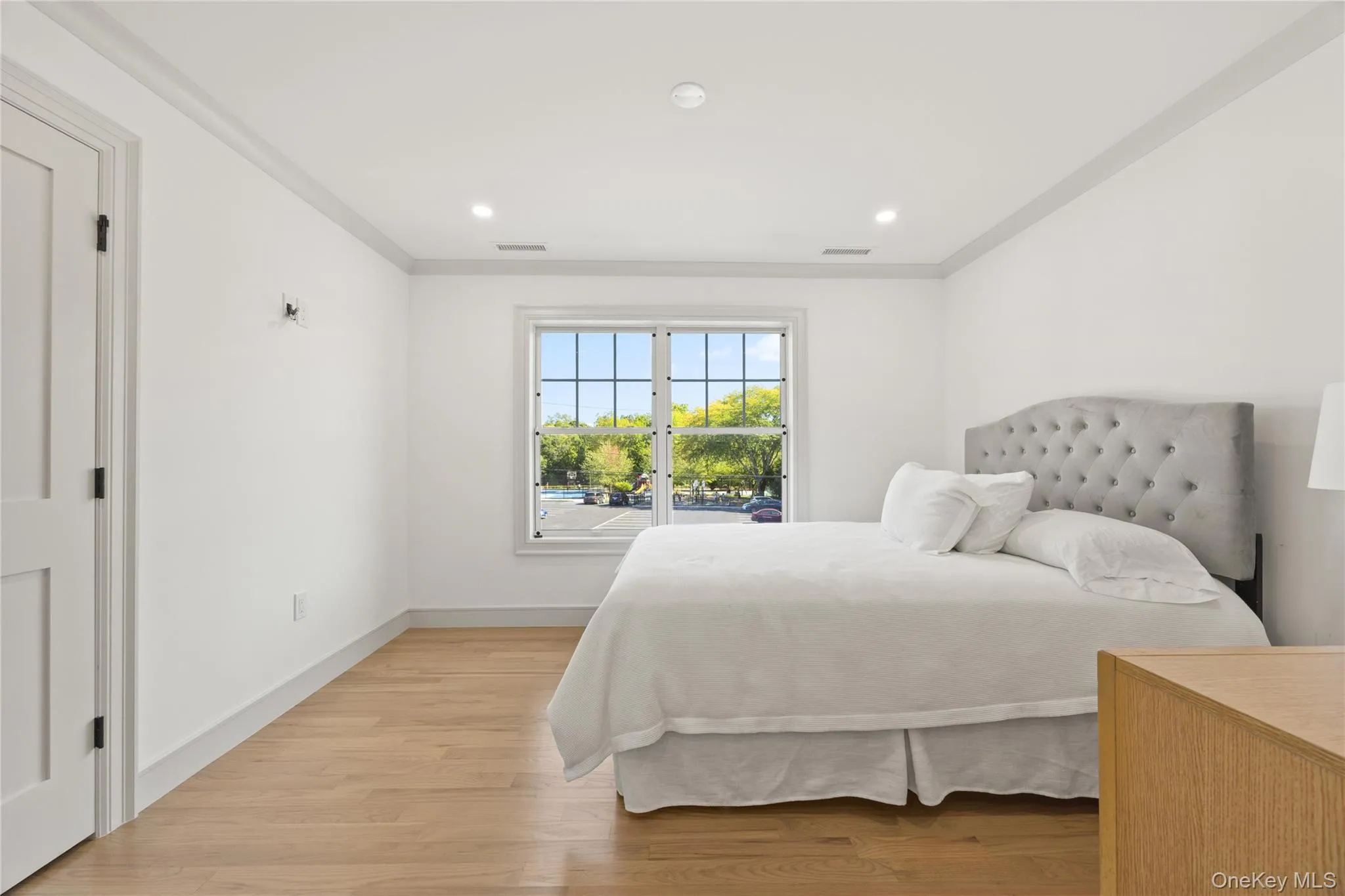 Bedroom with light wood finished floors, crown molding, and recessed lighting Bedroom with light wood finished floors, crown molding, and recessed lighting