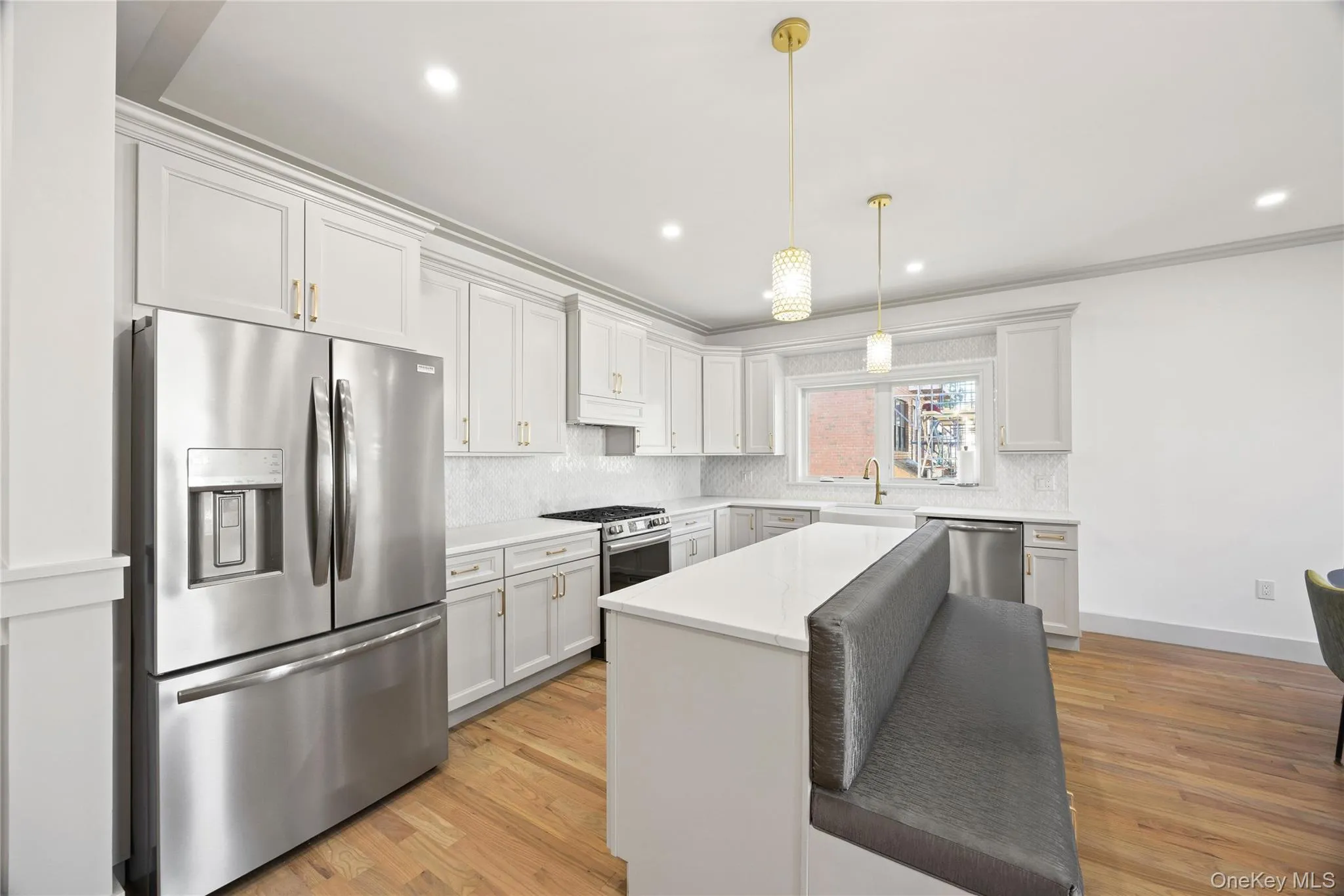 Kitchen featuring appliances with stainless steel finishes, crown molding, light wood-style flooring, a kitchen island, and pendant lighting Kitchen featuring appliances with stainless steel finishes, crown molding, light wood-style flooring, a kitchen island, and pendant lighting
