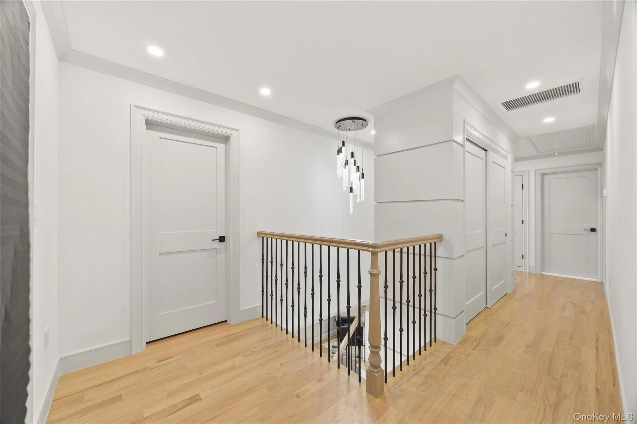 Hall with attic access, light wood-type flooring, recessed lighting, an upstairs landing, and ornamental molding Hall with attic access, light wood-type flooring, recessed lighting, an upstairs landing, and ornamental molding