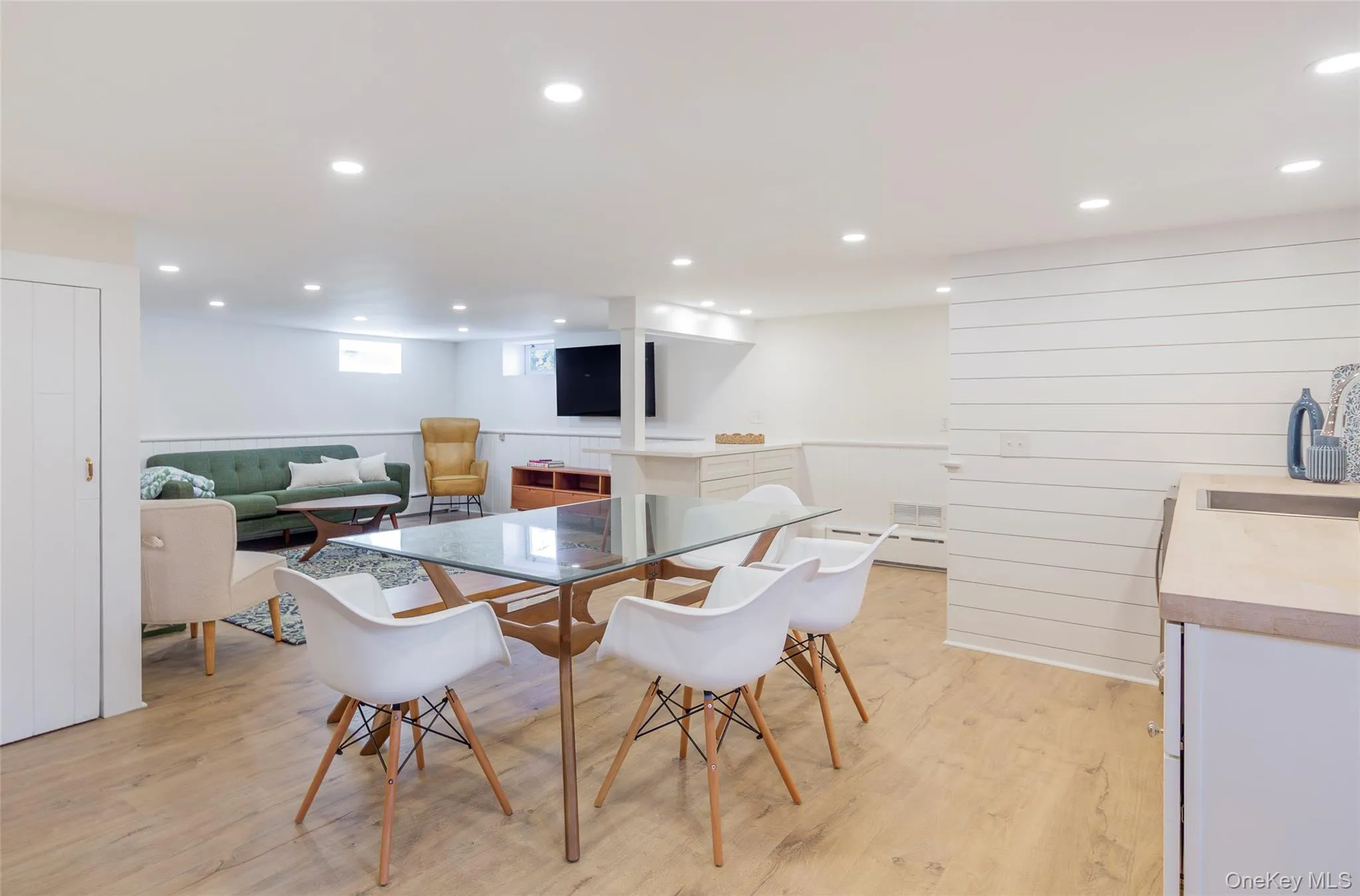 Dining room featuring light wood-style floors, recessed lighting, wood walls, a baseboard radiator, and a wainscoted wall Dining room featuring light wood-style floors, recessed lighting, wood walls, a baseboard radiator, and a wainscoted wall