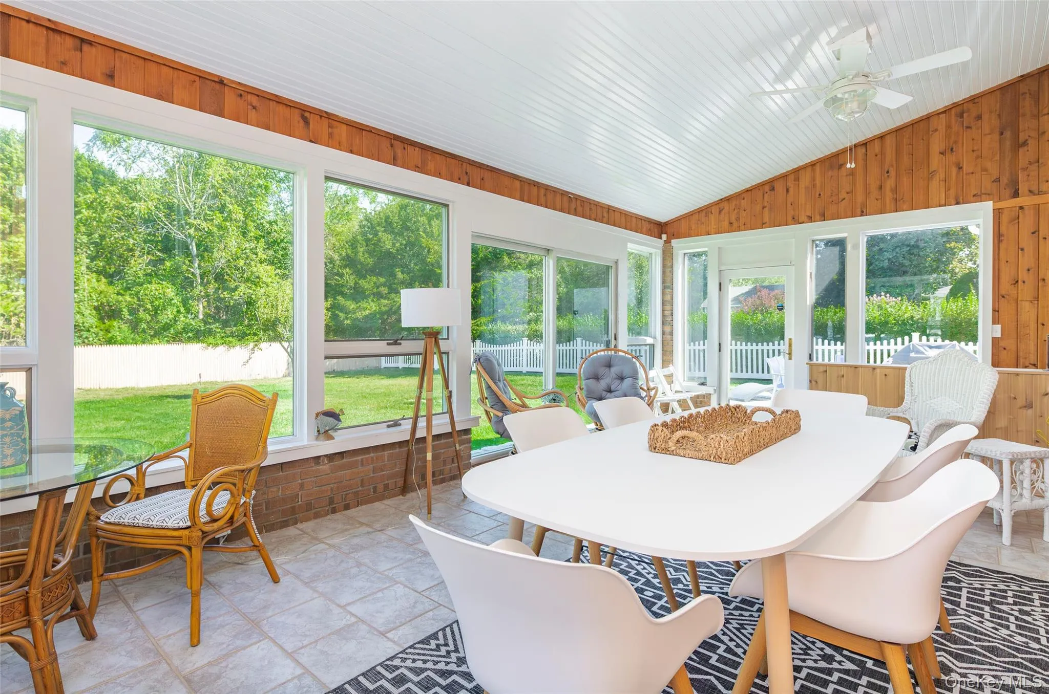 Sunroom / solarium with outdoor dining space, a ceiling fan, lofted ceiling, and wood walls Sunroom / solarium with outdoor dining space, a ceiling fan, lofted ceiling, and wood walls