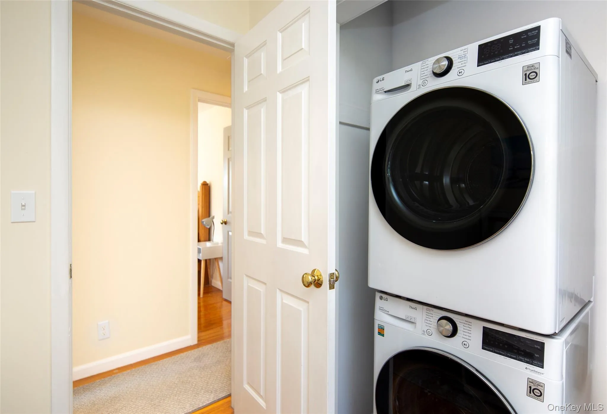 Laundry room with stacked washer and clothes dryer and wood finished floors Laundry room with stacked washer and clothes dryer and wood finished floors