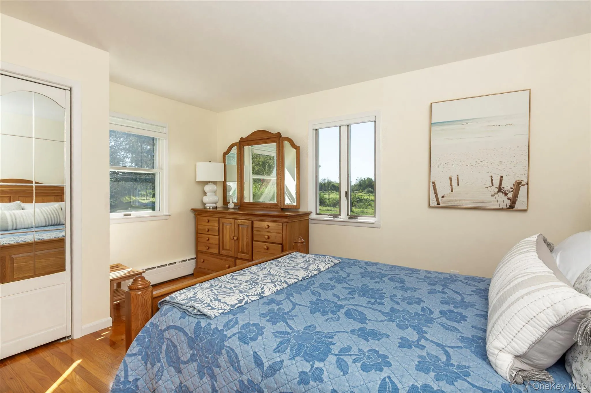 Bedroom featuring wood finished floors, baseboard heating, and a closet Bedroom featuring wood finished floors, baseboard heating, and a closet