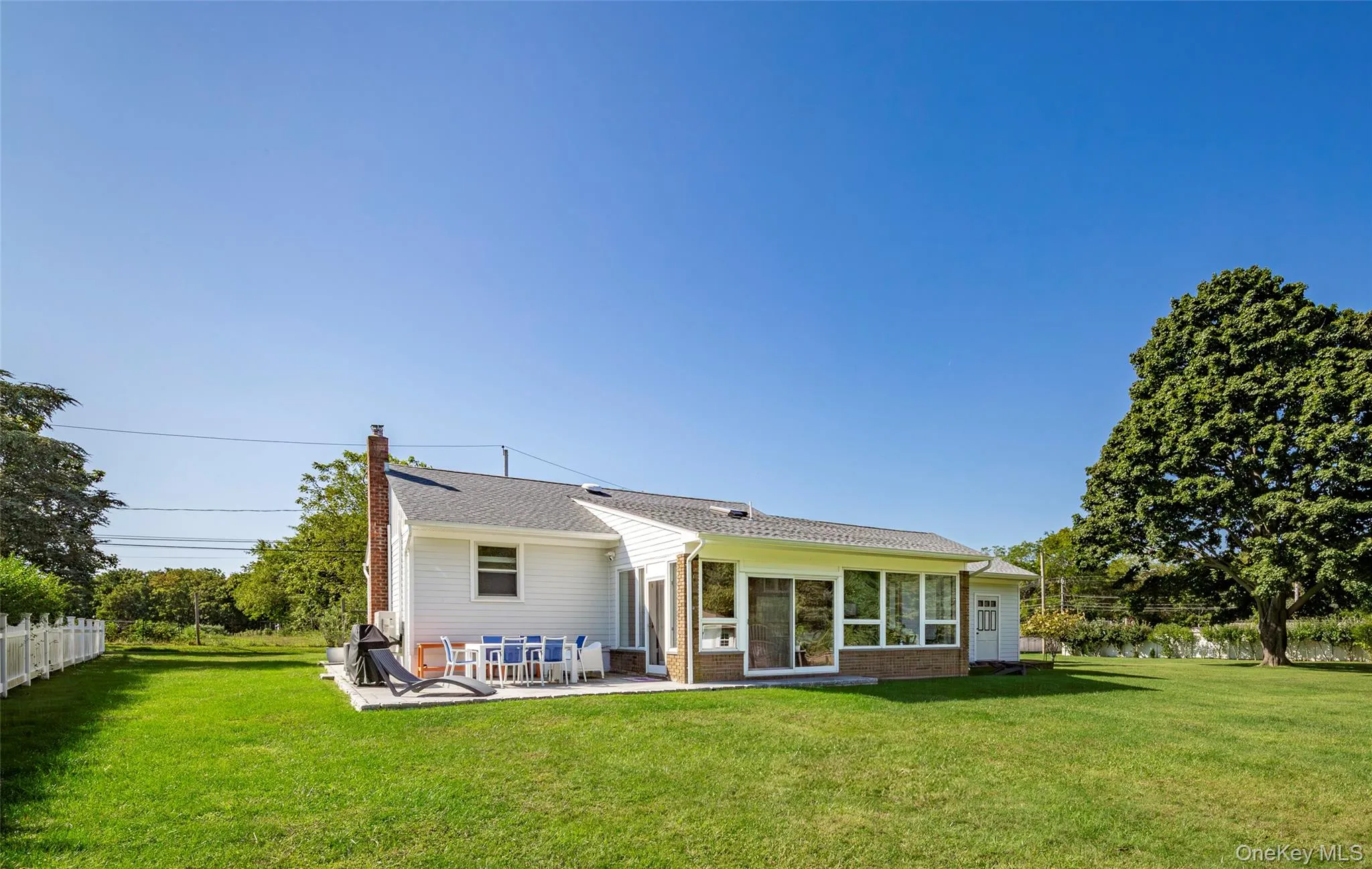 Back of house featuring a chimney, a patio, and brick siding Back of house featuring a chimney, a patio, and brick siding