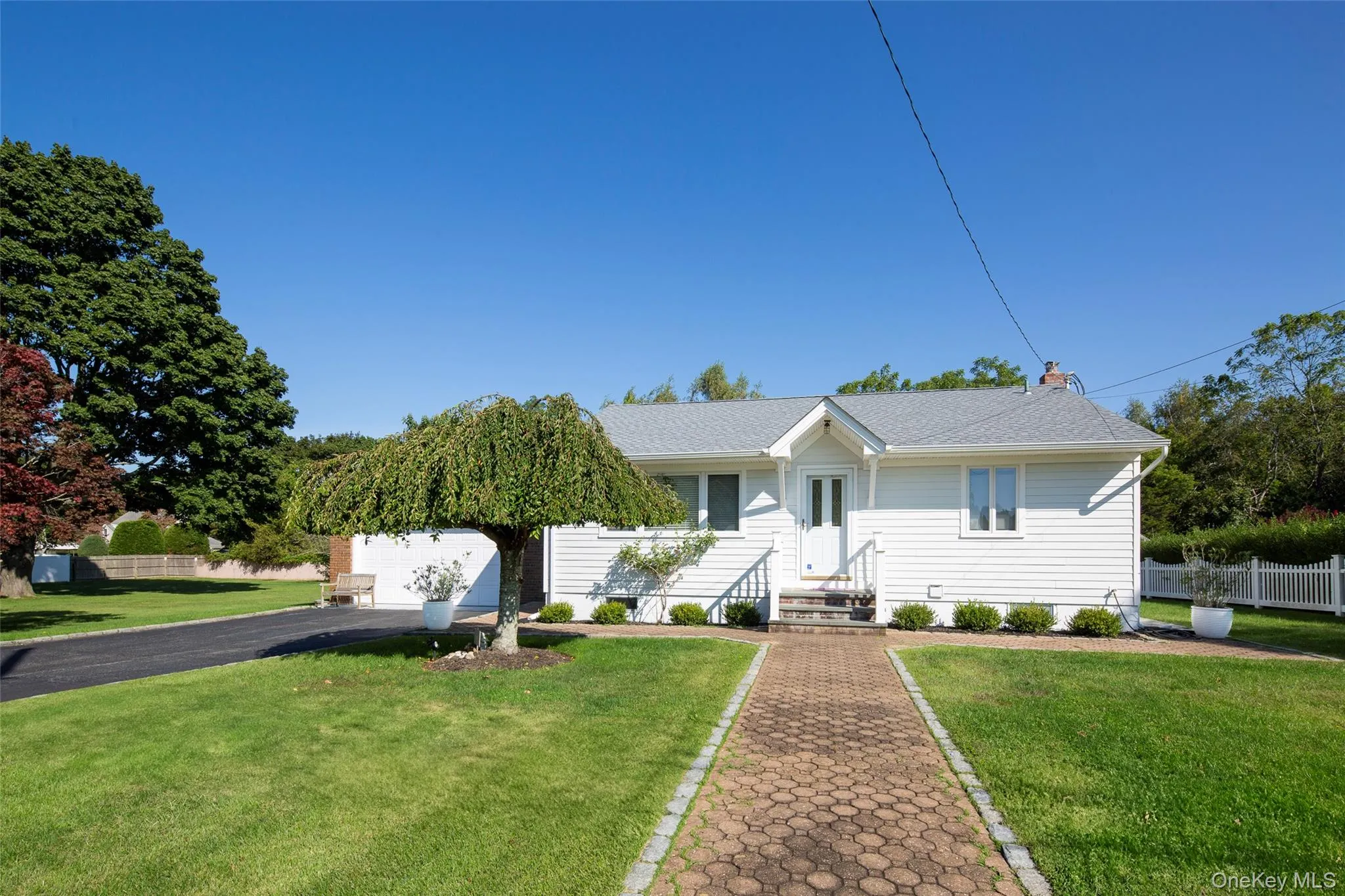 View of front of property featuring a garage, a chimney, asphalt driveway, and a shingled roof View of front of property featuring a garage, a chimney, asphalt driveway, and a shingled roof