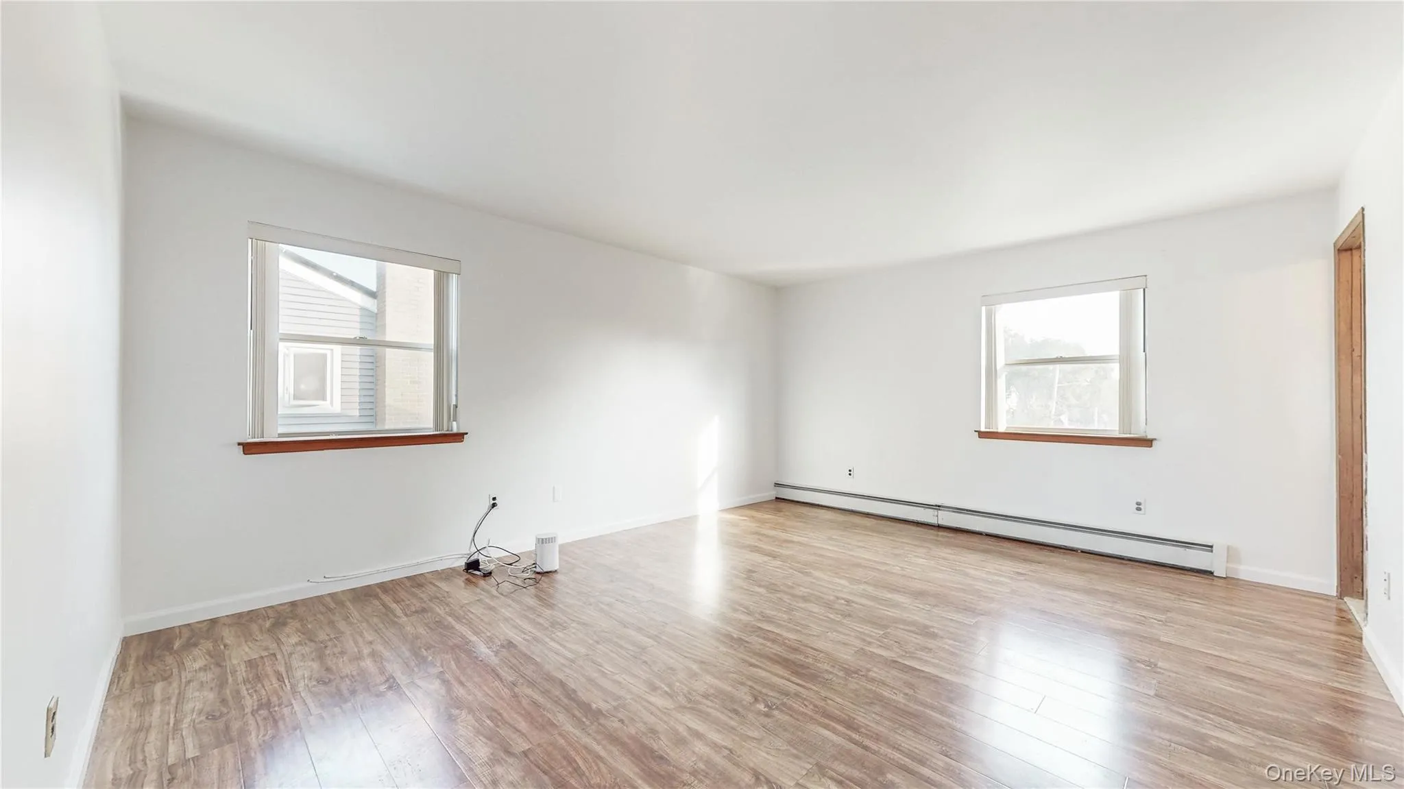 Empty room with a baseboard heating unit and light wood finished floors Empty room with a baseboard heating unit and light wood finished floors